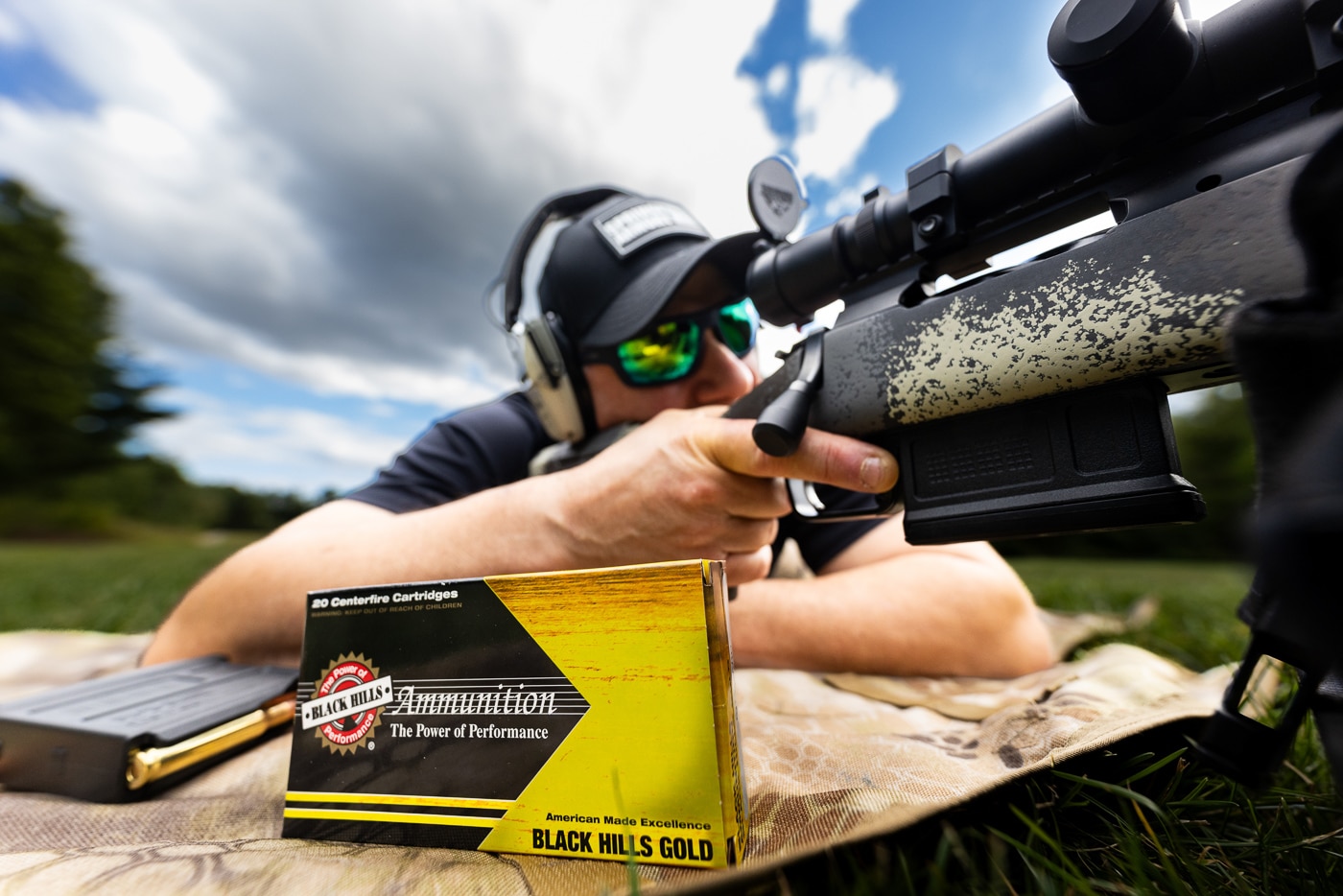 Shooter conducting Black Hills Gold .308 168-grain ELD ammo review at outdoor shooting range with precision rifle on benchrest. Testing Black Hills .308 Winchester ammunition loaded with 168-gr Hornady ELD Match bullets for accuracy and velocity measurements. Range evaluation of Black Hills Gold 308 ammo shows precision rifle cartridge performance. Ammunition testing setup includes chronograph for measuring muzzle velocity and standard deviation of .308 Win loads. Black Hills Ammunition 168 grain ELD Match bullet testing demonstrates company's reputation for accurate rifle ammunition. Outdoor range test of Black Hills Gold .308 cartridges with 168-gr projectiles. Precision shooting evaluation of Black Hills 308 Winchester ammo with ELD Match bullet technology. Black Hills Gold line represents premium hunting and target ammunition in .308 caliber.