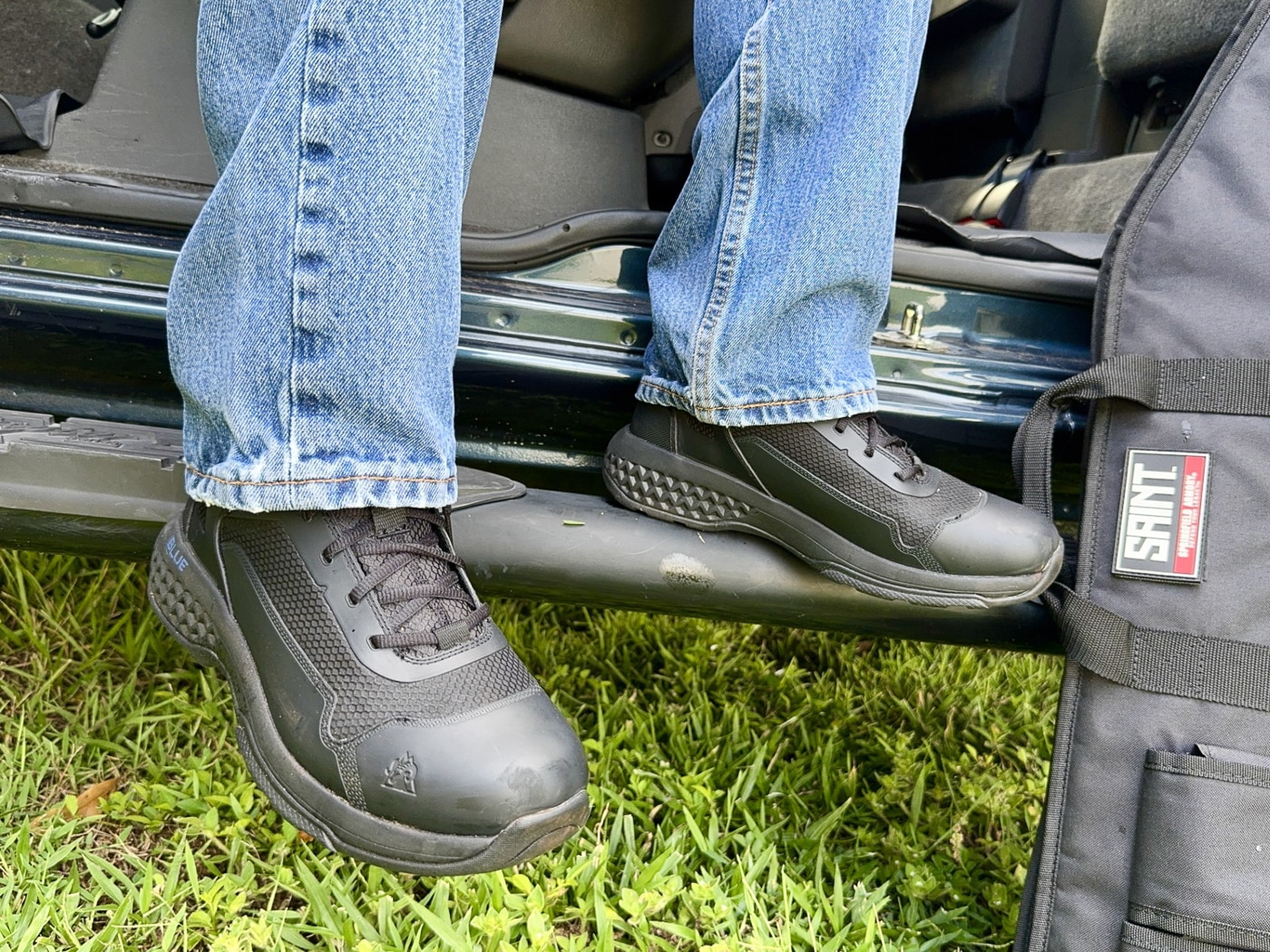 Police officer wearing Rocky Code Blue Public Service tactical boots during outdoor field testing showing real-world law enforcement duty footwear performance evaluation by experienced patrol professional. Author in black six-inch Rocky Boots demonstrates practical application during terrain navigation including drainage ditches overgrown scrub areas and chain-link fence climbing activities. Law enforcement officer testing budget-friendly tactical footwear under $98 MSRP showing oil-resistant slip-resistant rubber outsole performance on varied surfaces encountered during patrol work. Rocky Code Blue public safety boots worn during rigorous evaluation by police professional with 25 years experience and 12,000 miles on-duty walking running climbing through patrol activities. Six-inch non-waterproof breathable tactical boots tested by K9 officer and SWAT veteran demonstrating ankle support and mobility for active law enforcement duty scenarios. Police tactical footwear with TPU overlays and mesh construction shown in use during field work simulating daily patrol activities from city streets to outdoor terrain. Rocky Boots public service footwear evaluated through circuit training workouts including burpees lunges side-straddle hops and pull-ups accelerating typical boot wear patterns. Non-metallic tactical boots with removable Comfort Track footbed and EVA Rebound midsole worn during extended testing showing comfort requiring no break-in period for patrol officers.