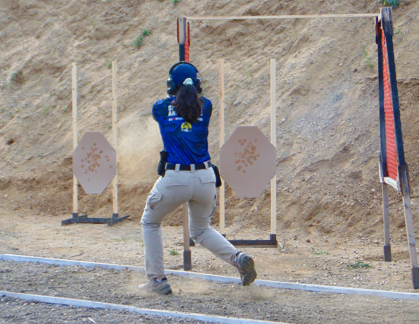 A competitor runs between shooting positions during a timed stage at the 2025 USPSA Collegiate Action Pistol Championships hosted by the Hillsdale Chargers shooting team at the John A. Halter Shooting Center in Michigan. The university action pistol athlete demonstrates the dynamic movement and speed required to navigate courses of fire at the Roger Ailes Action Pistol Shooting Center. Collegiate shooter moves quickly between target arrays while maintaining gun safety and control during their stage run at the Hillsdale College championship match. The university competitor represents the athletic demands of USPSA action pistol competition where shooters must combine marksmanship accuracy with physical agility at the Hillsdale Chargers facility. Action pistol athlete transitions between firing positions on one of the Springfield Armory sponsored stages that test tactical movement skills alongside shooting fundamentals. University shooting competitor demonstrates the fast-paced nature of practical shooting sports where stage times significantly impact overall scores at the Hillsdale competitive shooting event. The collegiate athlete represents shooters from 13 university teams including Texas A&M, Naval Academy, Virginia Tech who navigated similar challenging courses requiring both speed and precision. This university competitor's movement at the Hillsdale College championship illustrates why USPSA collegiate action pistol competition demands more than just static target shooting but complete tactical firearms proficiency.