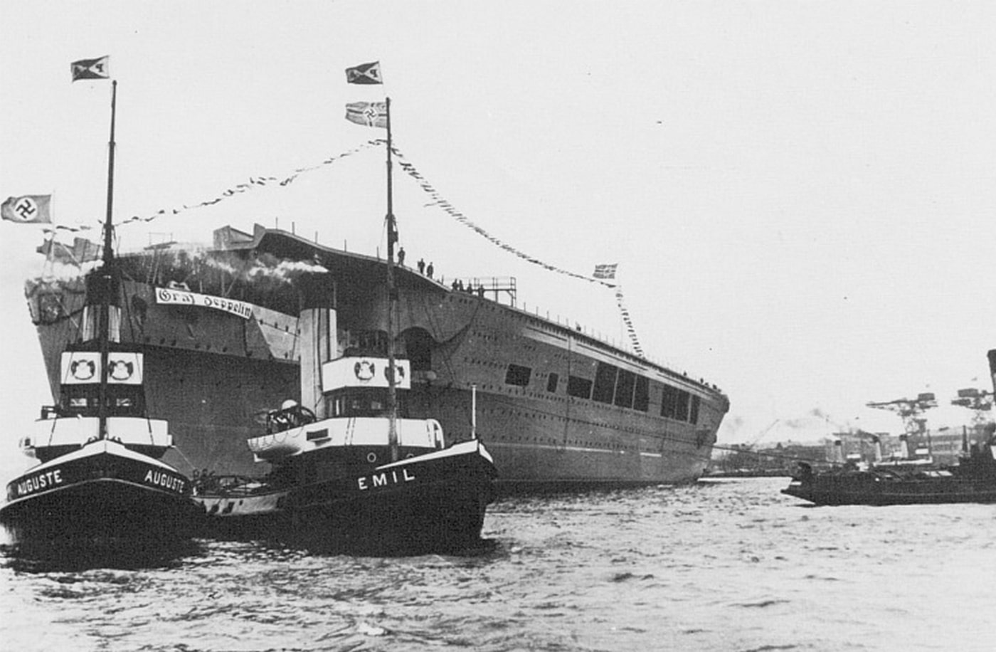 German aircraft carrier Graf Zeppelin keel laying ceremony Deutsche Werke shipyard Kiel Germany December 28 1936 showing Kriegsmarine flattop construction beginning. Hitler's carrier Graf Zeppelin construction started Slipway 1 naval architect Wilhelm Hadeler design displacement 19500 tons. Nazi Germany carrier program keel laid Third Reich naval aviation ambitions Kriegsmarine warship development. Graf Zeppelin-class aircraft carrier construction Deutsche Werke Kiel shipyard workers assembling initial framework December 1936. German carrier building program first purpose-built flattop warship Nazi naval forces World War II era construction commencement Anglo-German Naval Agreement tonnage limits.