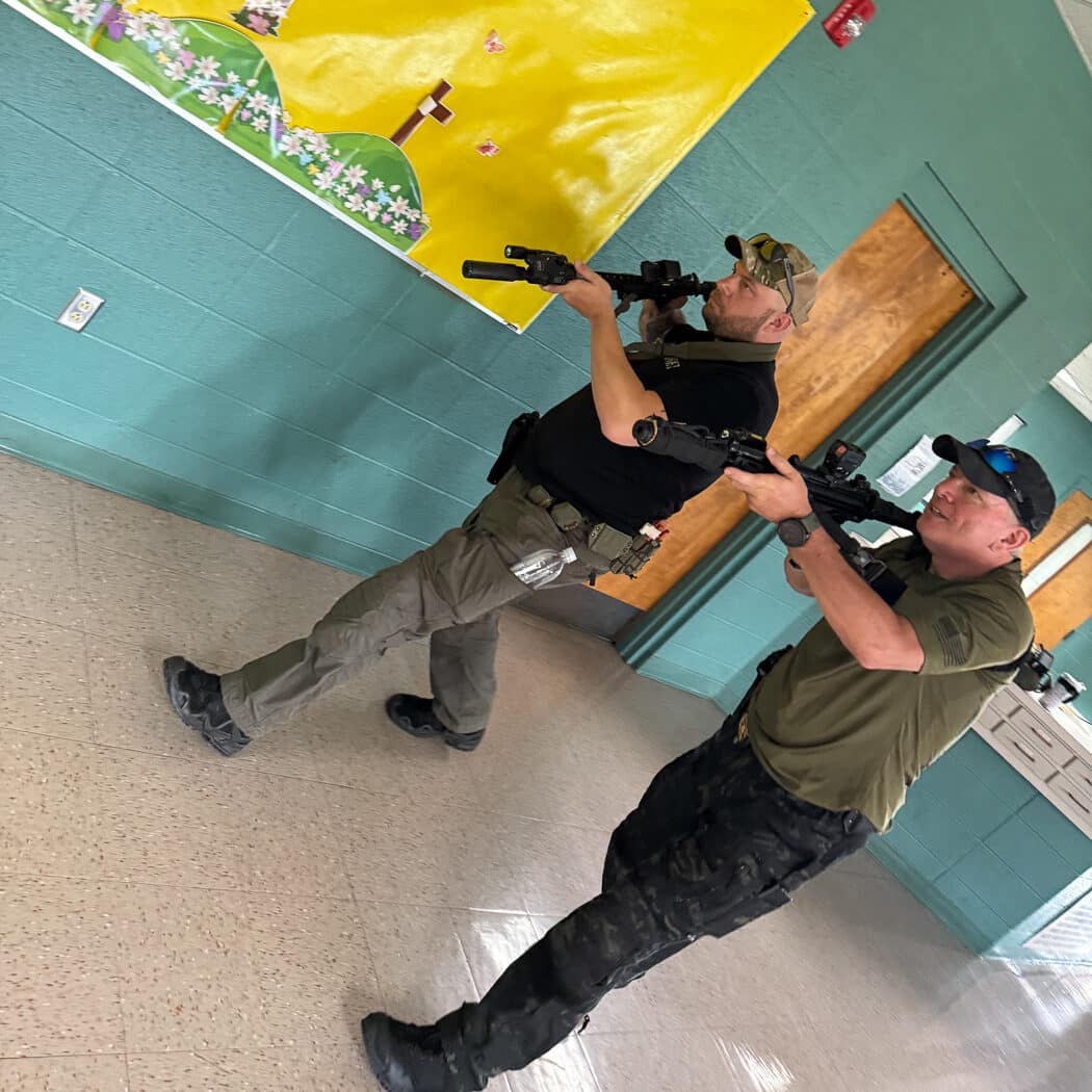 Law enforcement officers from small departments working as coordinated team to clear school building during Task Force 70 tactical training exercise. TF70 instructors teach rural police officers room clearing techniques, tactical movement patterns, and team communication methods for responding immediately to active threats in educational facilities. Small agency personnel practice patrol tactical operations for school emergencies where officers must intervene without waiting for specialized SWAT units that cannot reach rural communities quickly enough to prevent casualties in violent situations unfolding in classrooms, hallways, and public areas serving populations under 10,000 people with limited backup resources.