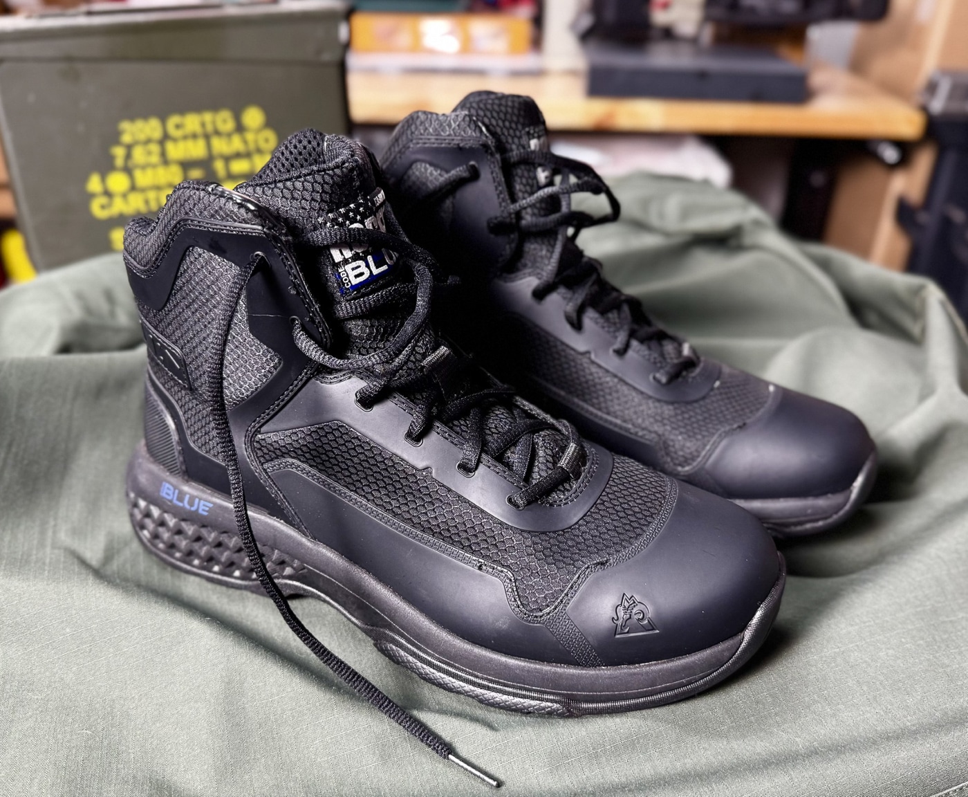 Side profile photograph of Rocky Code Blue Public Service six-inch tactical boot showing complete construction from oil-resistant rubber outsole to padded collar for law enforcement duty wear. Police patrol boot lateral view displays breathable mesh upper with thermoplastic polyurethane TPU overlay panels sewn and cemented creating lightweight durable tactical footwear. Rocky Boots public safety footwear side angle shows rectangular punched lacing holes through TPU material with oval laces providing secure lockdown without metal eyelets. Six-inch non-waterproof tactical boot profile demonstrates ankle support height suitable for patrol officers without excessive bulk of traditional eight-inch boots reducing heat retention. Non-metallic boot construction visible from side includes fiberglass shank EVA Rebound midsole and removable Comfort Track footbed providing stability and cushioning for extended shifts. Budget-friendly law enforcement boots under $98 MSRP show professional appearance from side profile suitable for city hall meetings uniform inspections and public-facing police duties. Black tactical boot side view reveals even seams quality stitching and solid bonding between rubber outsole mesh upper and TPU reinforced panels after rigorous testing. Rocky Code Blue patrol boot lateral profile shows padded collar and tongue construction providing comfort during circuit training workouts fence climbing and field work activities.