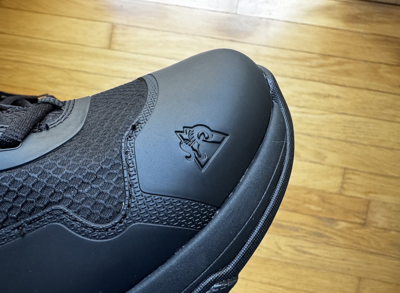 Rocky Code Blue Public Service boot toe cap detail showing thermoplastic polyurethane TPU overlay construction providing abrasion-resistant protection for law enforcement tactical footwear. Police duty boot toe area features TPU material sewn and cemented to breathable mesh upper creating durable lightweight alternative to traditional leather patrol boots. Six-inch tactical boot reinforced toe cap resists scuffing during field work including fence climbing drainage ditch navigation and scrub terrain traversal for police officers. Rocky Boots public safety footwear toe construction accepts shoe polish including black Kiwi polish creating high-gloss shine suitable for Class A uniform inspections and professional appearance. Non-metallic patrol boot toe cap demonstrates quality manufacturing with even sewing and seams bonding TPU overlay panels to cushiony mesh base material. Budget tactical boots under $98 MSRP feature toe protection comparable to expensive law enforcement footwear using advanced synthetic materials instead of full leather construction. Oil-resistant slip-resistant rubber outsole connects to TPU reinforced toe area showing solid construction after months of accelerated wear testing through circuit training. Abrasion-resistant toe cap on Rocky Code Blue boots protects against daily patrol activities including kicking doors searching fields and physical confrontations encountered by police officers.