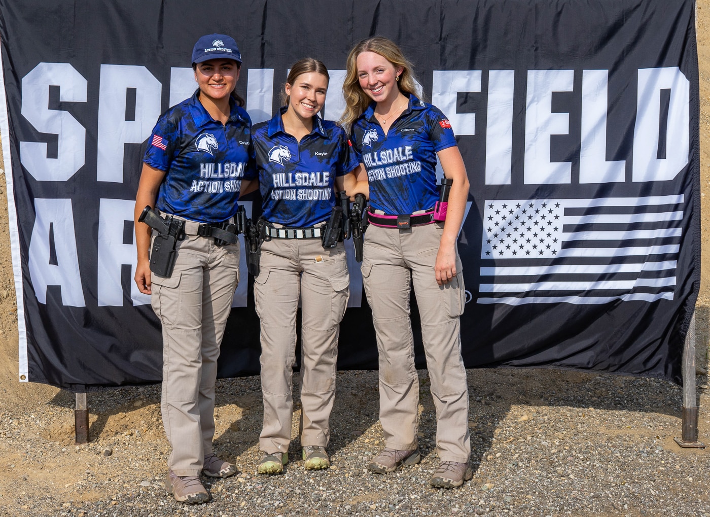 Three members of the Hillsdale College competitive action pistol team stand together representing the women athletes who compete for the Chargers shooting program. The Hillsdale marksmanship team women competed at the 2025 USPSA Collegiate Championships held at their John A. Halter Shooting Center home facility in Michigan. These Hillsdale Chargers pistol shooters participated in matches against teams from Texas A&M, Naval Academy, Virginia Tech, Michigan State, and other universities. The women from Hillsdale's shooting team helped secure second place Limited team scores and strong individual performances in collegiate practical shooting competition. Hillsdale College action pistol program athletes like these women shooters have contributed to the growth of their range facility into a premier national competition site. The Hillsdale competitive shooting team members represent a program that has won championships and continues attracting more collegiate teams to compete at the Roger Ailes Action Pistol Shooting Center. These women athletes from the Hillsdale Chargers demonstrate the skill and dedication that makes their university's marksmanship program a leader in USPSA collegiate action pistol sports.