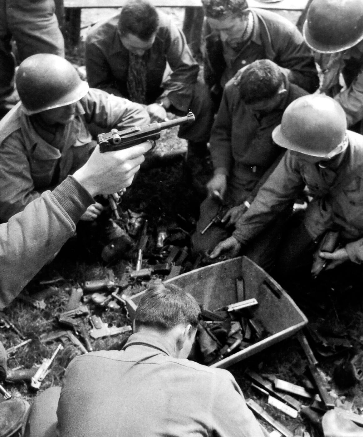 A U.S. 9th Air Force serviceman in military uniform proudly displays a captured German Luger pistol while stationed in France during World War II operations. War trophy collecting extended beyond infantry ranks. Airmen sought enemy firearms eagerly. Captured pistols appealed to all services. Trophy weapons crossed military branches. War souvenirs mattered to aviation personnel. Seized Lugers represented universal desires. Trophy sidearms validated diverse combat roles. Military keepsakes connected airmen to ground victories.