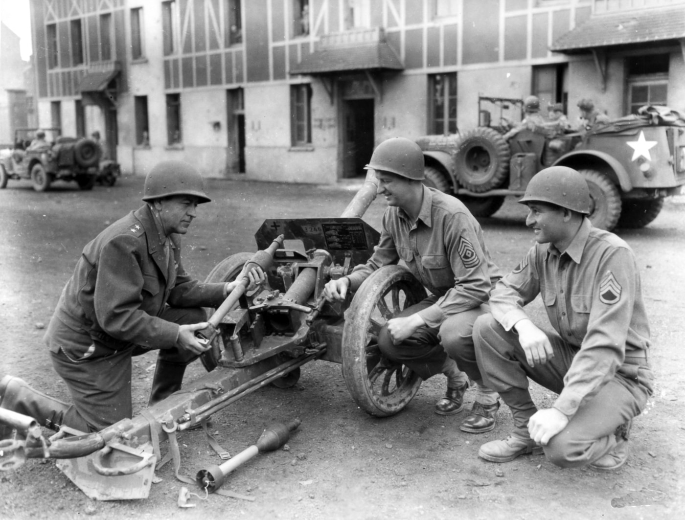 American Major General Henry Benton Sayler bends down to closely examine a captured 8.8cm Raketenwerfer 43 Püppchen anti-tank rocket launcher during World War II operations in France. US generals inspected captured German weapons. The Püppchen interested American ordnance leadership. Allied commanders studied enemy anti-tank technology. Major General Sayler examined the Raketenwerfer 43 firsthand. American officers assessed German rocket launchers. The captured Püppchen provided valuable intelligence. US Army leadership reviewed enemy equipment. German anti-tank weapons received high-level attention.