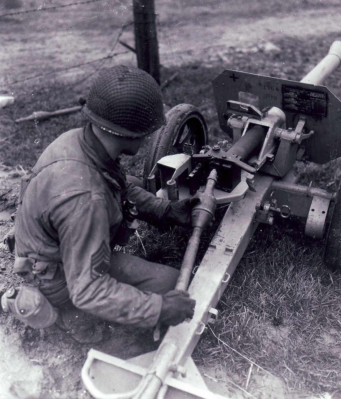 An American GI closely examines an 8.8cm RPzBGr 4312 rocket projectile, the percussion-fired ammunition used by the German Raketenwerfer 43 Püppchen anti-tank launcher. US soldiers inspected German rocket ammunition. The RPzBGr 4312 used percussion cap ignition. American troops examined captured Püppchen rockets. The 88mm projectile featured a hollow charge warhead. German rocket ammunition interested Allied forces. The Raketenwerfer 43 fired modified Panzerschreck rounds. GIs studied enemy anti-tank projectiles. Percussion primers replaced electrical ignition systems.