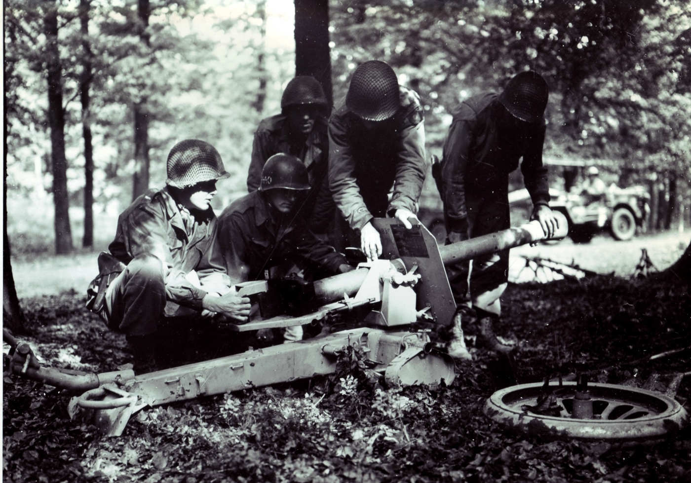 American soldiers from the 9th Infantry Division gather around to inspect a captured 8.8cm Raketenwerfer 43 Püppchen anti-tank rocket launcher during World War II operations. The 9th Infantry Division encountered German rocket weapons in combat. US soldiers examined captured Püppchen launchers. American GIs learned about enemy anti-tank technology. The Raketenwerfer 43 was unfamiliar to most infantrymen. Wehrmacht forces used rocket launchers against the 9th Division. Allied troops inspected German equipment after capture. The 88mm launcher drew considerable soldier interest. US infantry units faced Püppchen crews in battle.