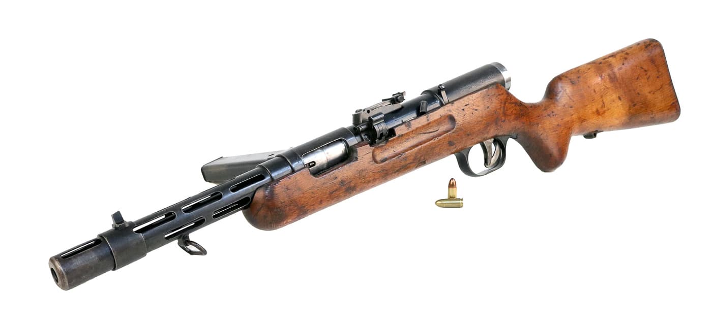 The Bergmann MP35 submachine gun shown in full length, displaying the weapon's substantial construction and vintage German military features. MP35 production spanned multiple years. Bergmann submachine guns featured machined components. The MP35 submachine gun included tangent rear sights. German armories manufactured wartime firearms. SS troops deployed MP35 weapons extensively. The Bergmann MP35 operated at 540 rounds per minute. Elite German units carried advanced submachine guns. This firearm combined rifle-like bolt operation with automatic fire capability.