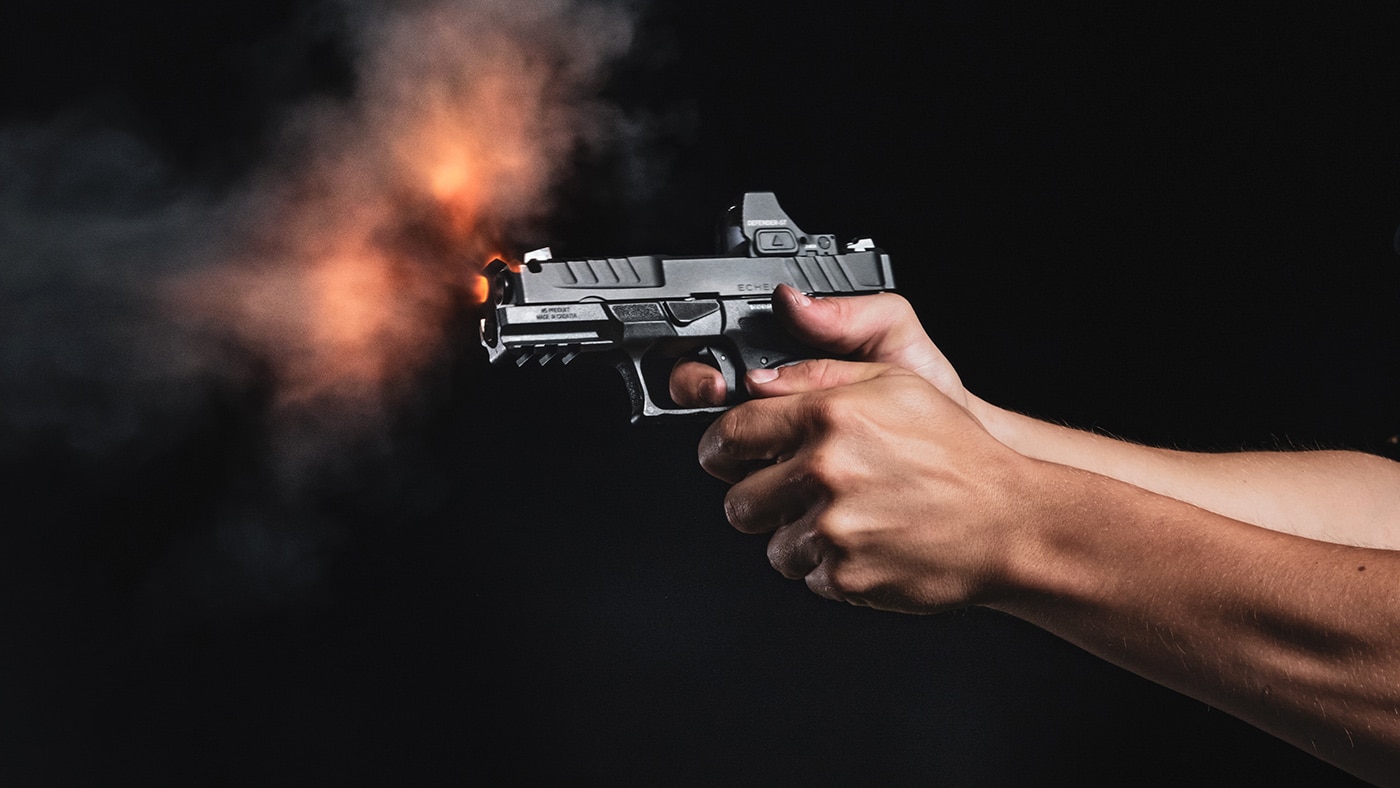 Person shooting a pistol with flash of fire out the barrel