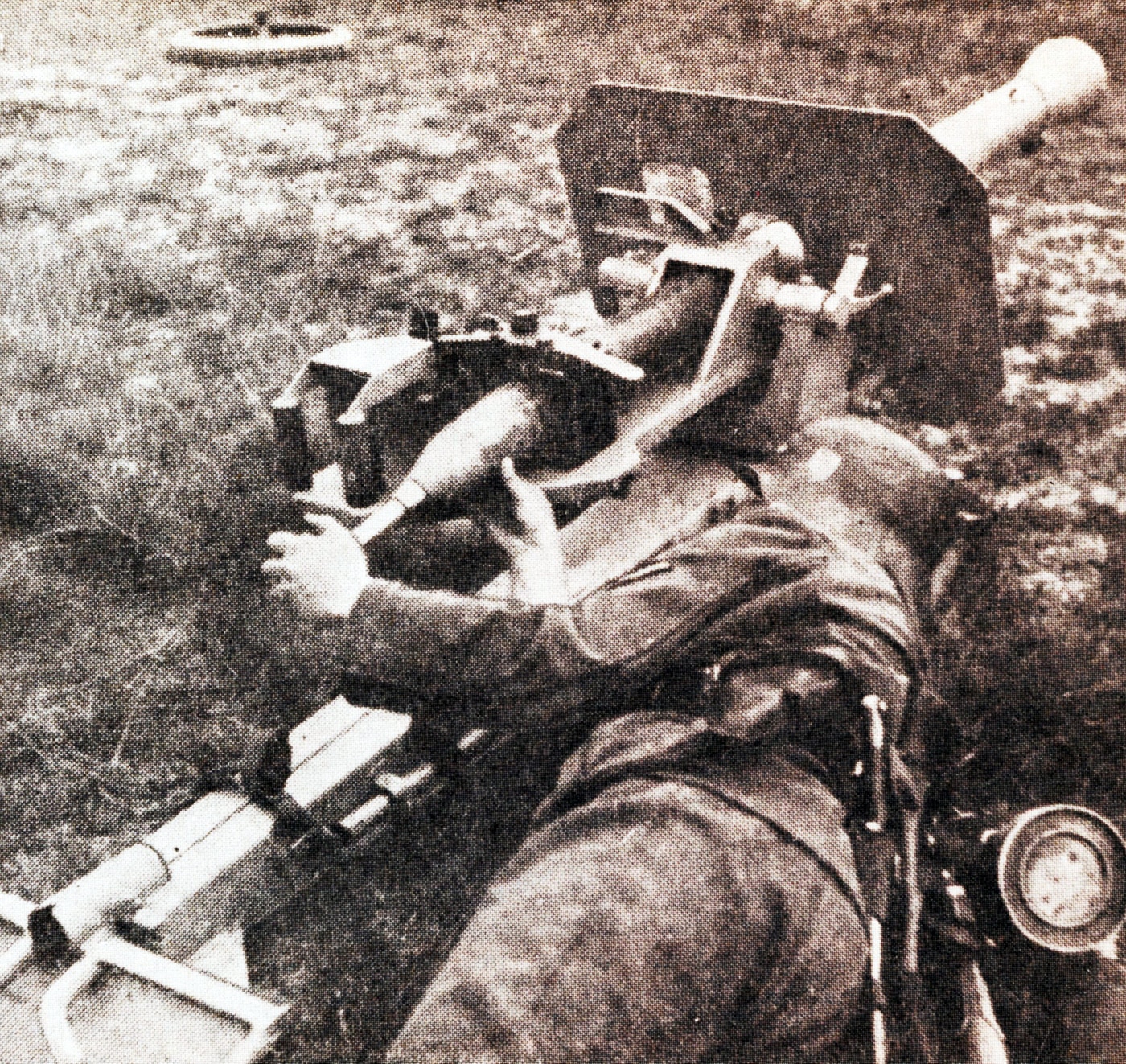 A German soldier in World War II uniform loads an 88mm rocket projectile into the open breech of a Raketenwerfer 43 Püppchen anti-tank launcher. The Püppchen used a sliding breechblock mechanism. German crews loaded rockets from the rear. The 8.8cm projectile featured a percussion primer. Wehrmacht soldiers operated anti-tank rocket launchers. The Raketenwerfer 43 fired hollow charge ammunition. Loading the Püppchen required opening the breech handle. German anti-tank teams engaged Allied armor. The closed breech contained rocket exhaust gases.