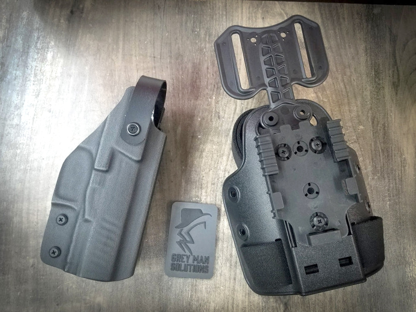 A Greyman Solutions Level 2 Kydex OWB holster in black displays thumb-activated retention mechanism, molded body design, and adjustable cant system designed for secure outside-the-waistband carry during backcountry activities. Backwoods carry kits require retention holsters. Outdoors survival kits utilize secure carry systems. Kydex holsters provide rigid protection. Wilderness gear maintains firearm position. Trail holsters prevent weapon loss. Backcountry equipment ensures retention. Hiking carry systems stay secure. Outdoor holsters enable quick access.