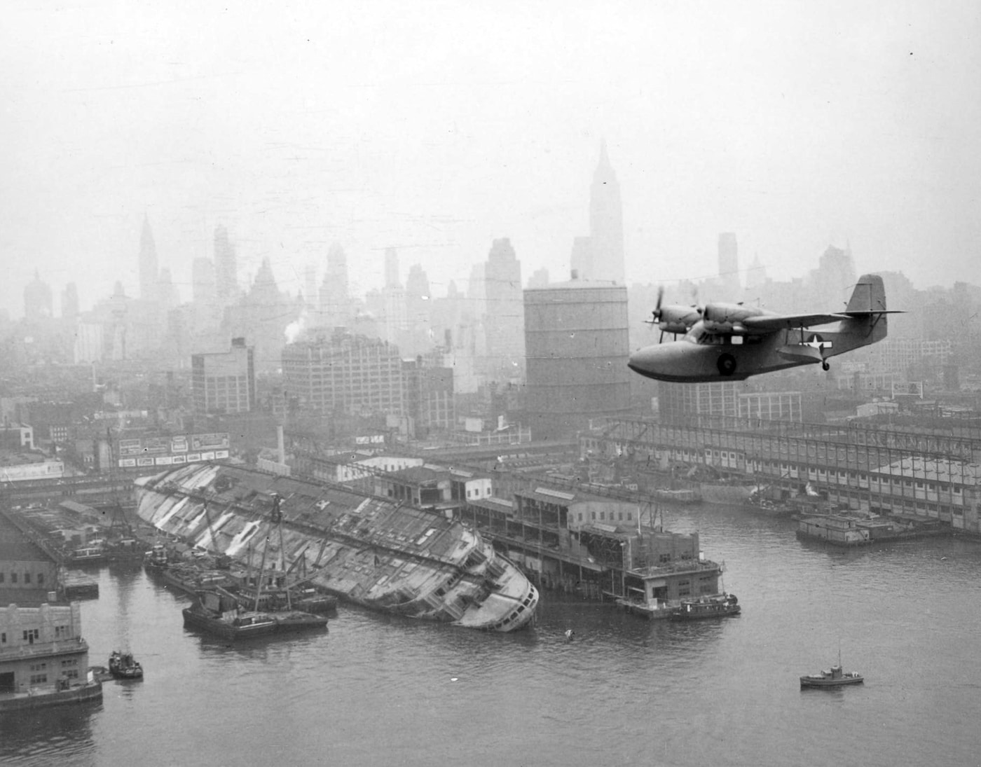 A Grumman J4F Widgeon patrol aircraft flies low over the capsized hull of the USS Lafayette in New York Harbor, surveying the maritime disaster below. Operation Underworld emerged directly from this catastrophic security failure in 1942. Mafia role in World War II began with preventing similar sabotage incidents. The Lafayette capsizing exposed glaring vulnerabilities in port protection measures. Naval Intelligence realized conventional law enforcement couldn't secure waterfront operations adequately. Criminal networks offered surveillance capabilities that government agencies lacked completely. Lucky Luciano's influence over docks became strategically valuable after this disaster. The collaboration between federal authorities and mobsters prevented future attacks. This wreckage symbolized the urgent need for unconventional security solutions.