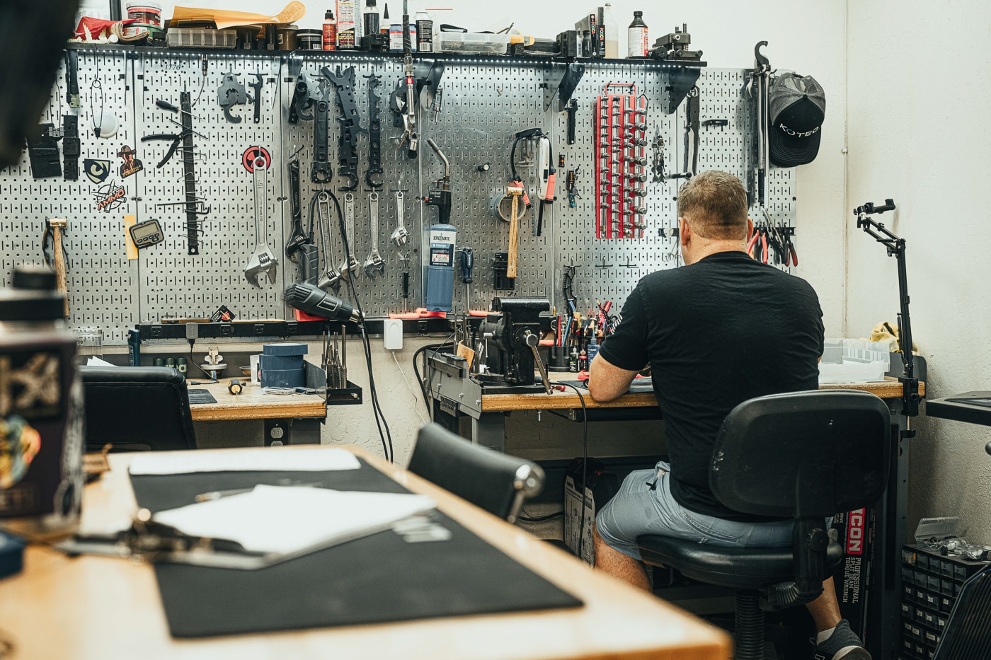 An industrial workshop contains specialized finishing equipment, workstations, and machinery used for custom firearms coating, engraving, and metal treatment processes. The Koted interview reveals operational infrastructure investments. Koted Custom Finishings operates comprehensive production facilities. Interview of Koted discusses equipment acquisition strategy. Automated polishing systems increase volume capacity. Koted interview explains complementary service integration advantages. Laser machines enable part marking capabilities. The interview of Koted covers scalable precision execution. Koted maintains competitive turnaround time standards.