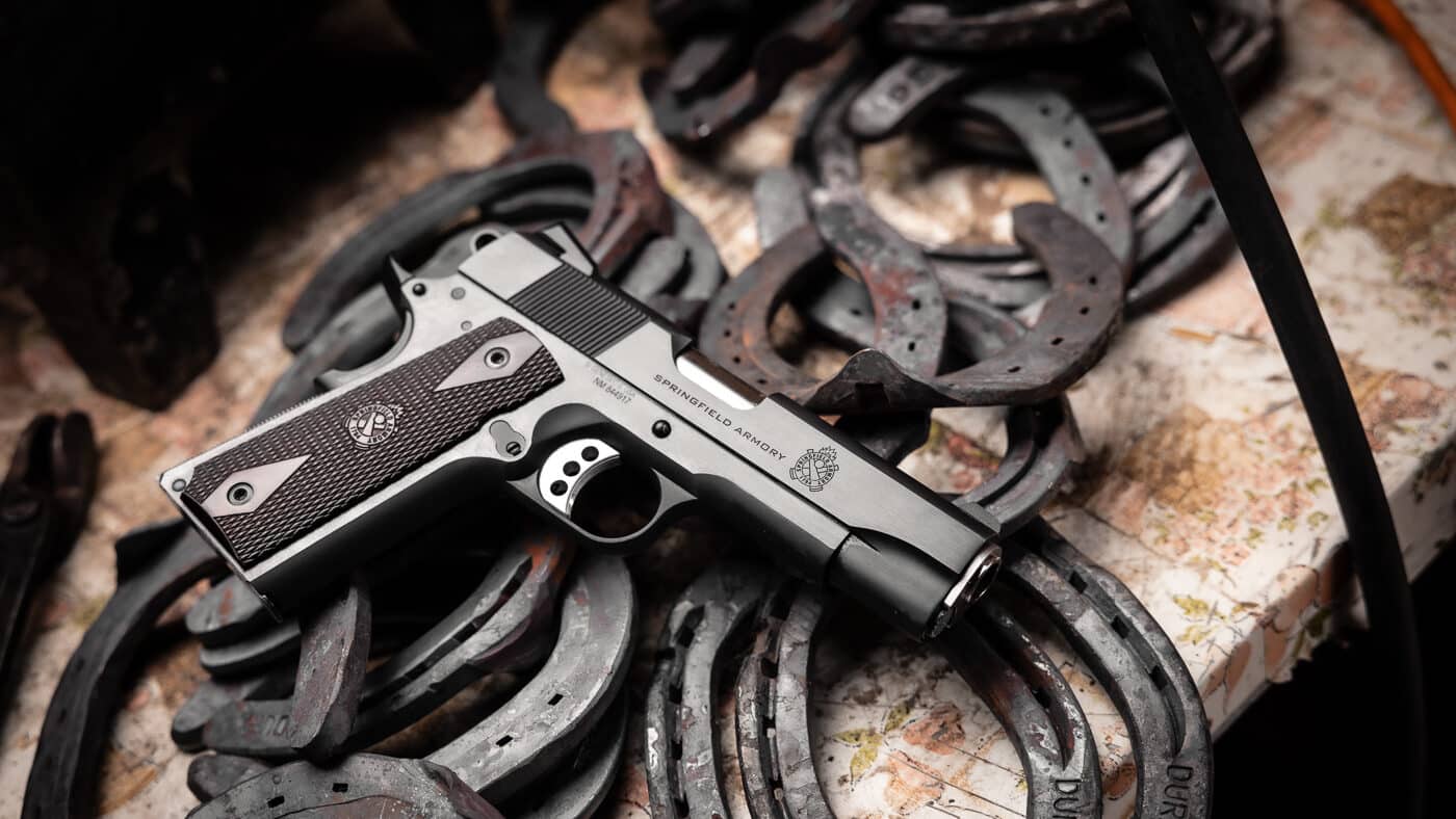 A Springfield Armory Garrison 1911 pistol in stainless steel finish displayed with outdoor gear and ammunition against a rustic wooden background. M1911 pistols serve effectively as woods guns for backcountry defense. Springfield Armory Garrison exemplifies ideal M1911 characteristics. Stainless steel construction resists environmental damage. Woods carry demands reliable defensive firearms. The .45 ACP cartridge stops dangerous wildlife. Field-ready pistols combine durability with performance. Ranch guns require proven dependability. Outdoor enthusiasts trust traditional designs.