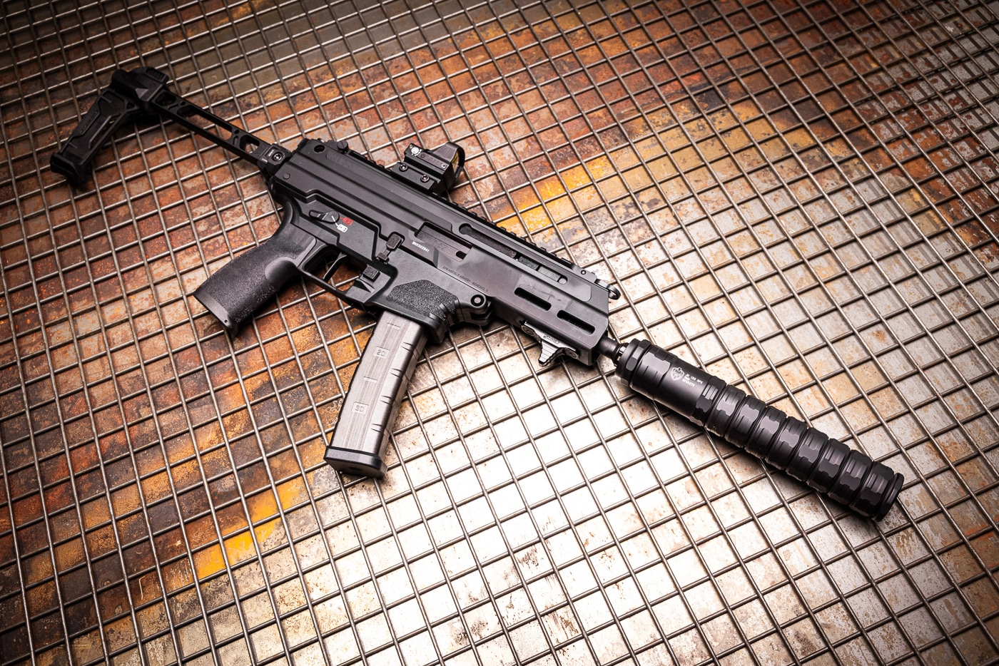 A photograph of the Springfield Armory Kuna pistol caliber carbine with the JK Armament 155 RPX 9mm suppressor mounted on the threaded barrel. The JK Armament suppressor review tested the Kuna extensively. Pistol caliber carbines benefit from sound suppressors. The RPX 9mm silencer reduced muzzle blast noticeably. Suppressed fire improves shooter comfort on the range. The Kuna provides a stable platform for rapid shooting. Longer barrels enhance suppressor effectiveness. The modular can attaches securely via taper mount. This sound suppressor softens the recoil impulse considerably.