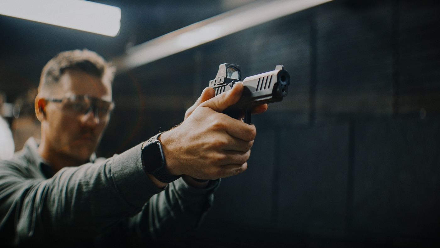 A man aims and fires the Springfield Prodigy Compact at a shooting range. The Springfield Prodigy Compact review covers extensive live-fire testing. This compact 1911 DS pistol chambered in 9mm impressed evaluators. The double-stack design increases magazine capacity. Springfield Armory built this handgun for everyday carry. The Prodigy Compact delivers sub-inch accuracy groups. Range sessions confirm the pistol's reliability. The compact frame balances concealability with shootability. This 1911-style firearm suits defensive and competition use.