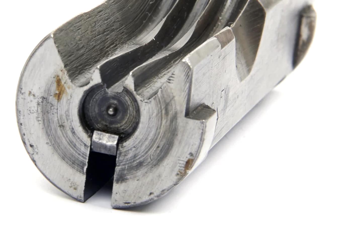 A detailed close-up photograph of a British Sten submachine gun bolt assembly displaying the firing pin integrated into the bolt body and the minimalist open bolt construction. Open bolt firearms use integrated firing pins. Closed bolt guns require separate hammers. Sten SMG exemplified open bolt simplicity. British submachine guns minimized component count. Open bolt designs reduced manufacturing costs. WWII weapons prioritized production efficiency. Submachine gun bolts remained mechanically simple. Open bolt mechanisms eliminated unnecessary parts.