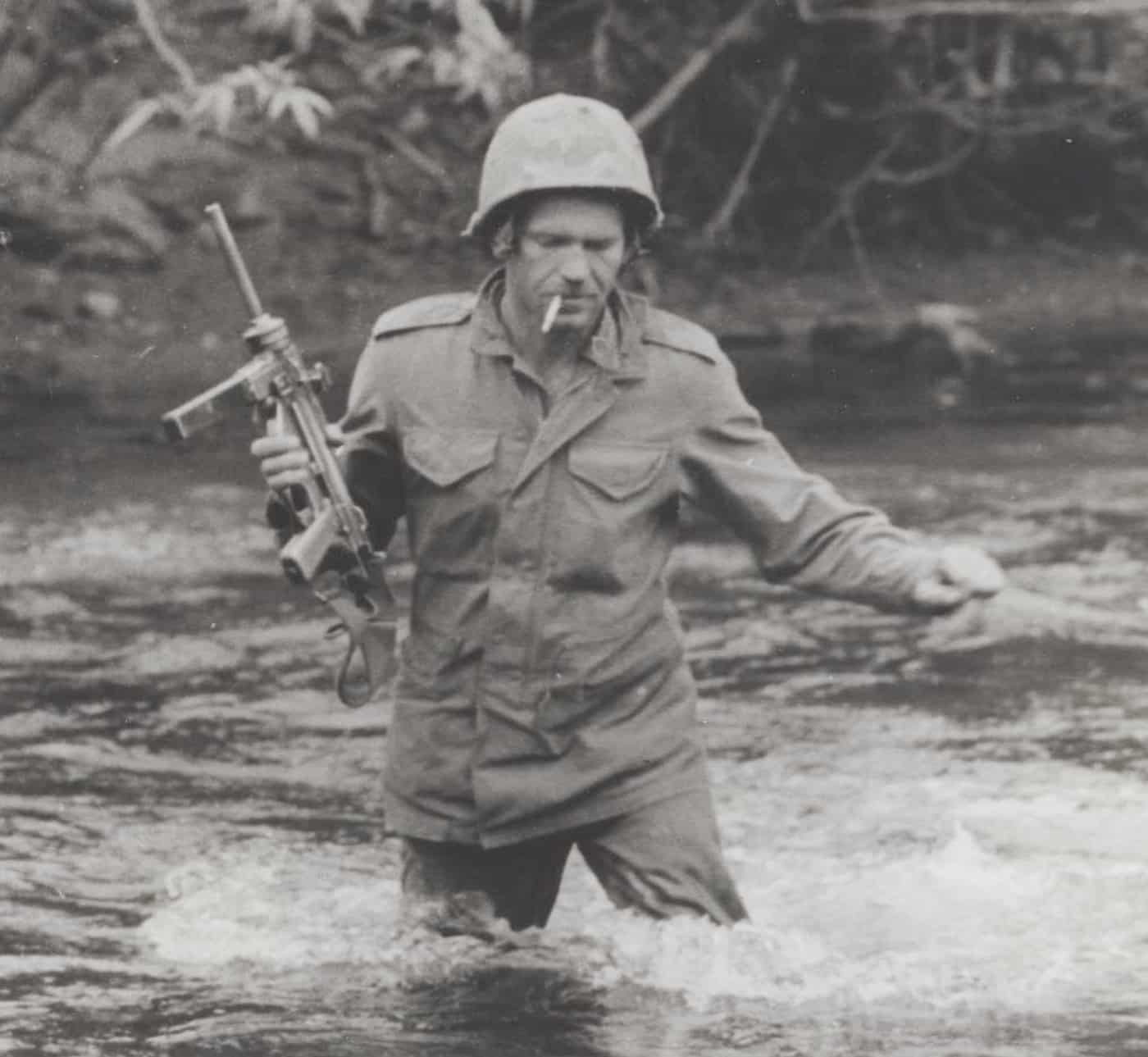 Sergeant Bruce E. Strickler wading through the Cu De River while carrying an M3A1 Grease Gun submachine gun during a patrol mission into Elephant Valley searching for Viet Cong positions. Open bolt firearms withstood harsh environments. Closed bolt guns required more maintenance. M3A1 Grease Gun featured open bolt reliability. Vietnam War weapons endured extreme humidity. Open bolt designs handled adverse conditions. Jungle combat demanded dependable firearms. Submachine guns served multiple military conflicts. Open bolt mechanisms rarely malfunctioned.