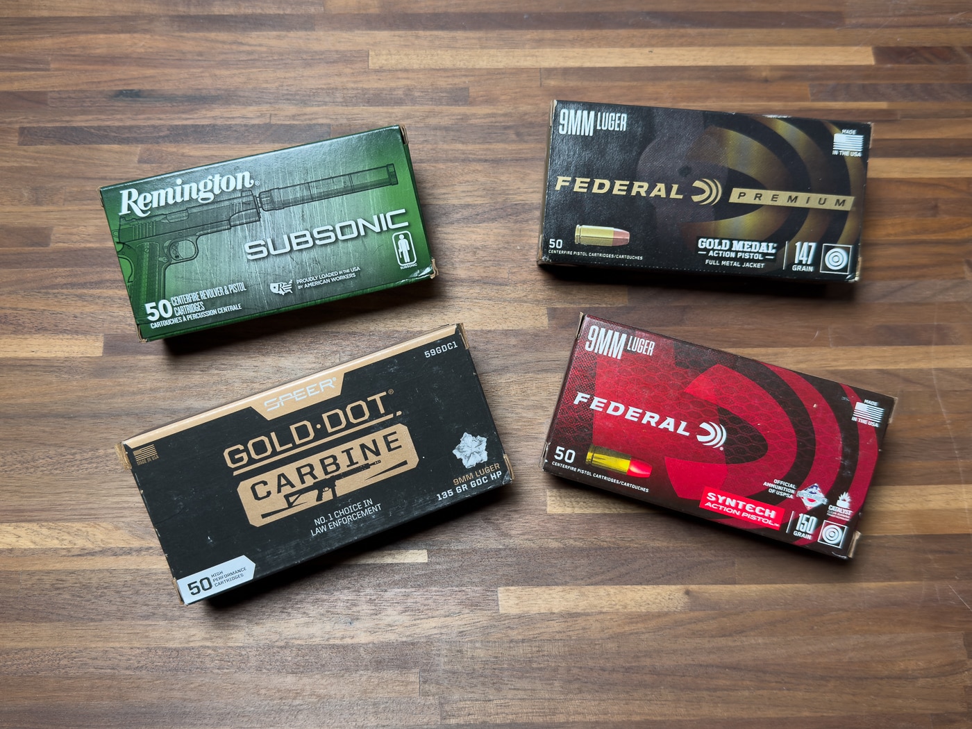 A photograph displaying the various boxes and cartridges of 9mm ammunition used during the JK Armament 155 RPX suppressor evaluation including Federal, Remington, and Speer loads. The JK Armament suppressor review tested multiple ammunition types. Subsonic rounds minimize the supersonic crack effectively. Heavier bullets stay below the sound barrier reliably. Federal Gold Medal provides match-grade consistency. Remington Subsonic offered the quietest performance overall. Speer Gold Dot Carbine optimizes for longer barrels. Ammunition selection impacts suppressor sound reduction significantly. Shooters should match loads to their suppressed setup.