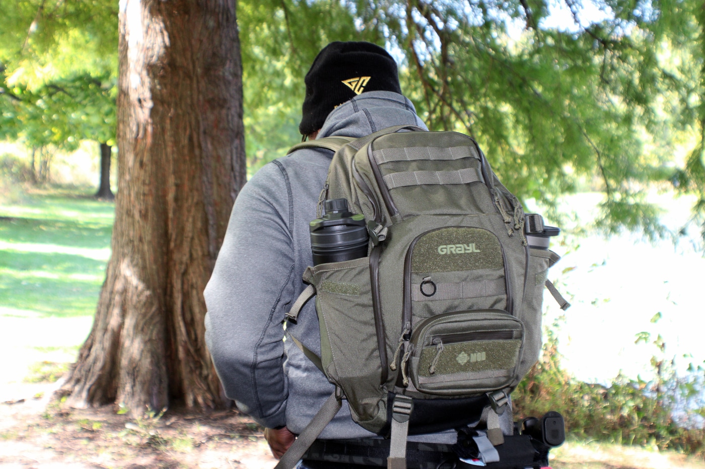 A rugged outdoor daypack in earth tones sits ready with gear, featuring external straps, durable construction, and multiple compartments designed for wilderness travel. Backwoods carry kits require proper transportation. Outdoors survival kits need durable packs. Daypack systems organize essential gear. Hiking equipment demands reliable storage. Wilderness packs balance weight distribution. Trail bags provide accessibility. Backcountry containers protect supplies. Outdoor pack systems enhance readiness.