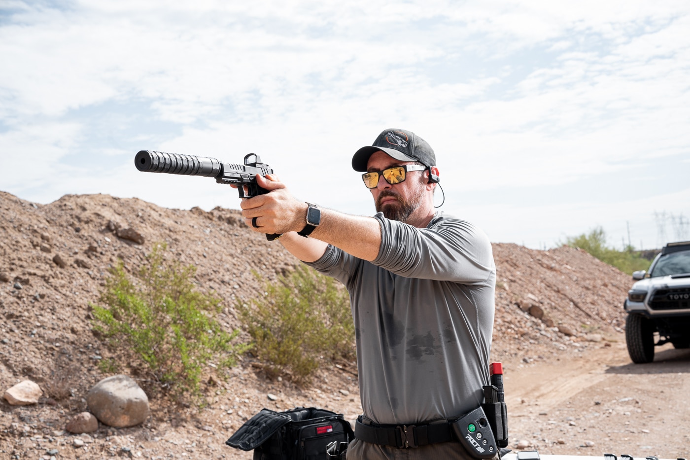 An action photograph showing the reviewer shooting the suppressed Springfield Echelon handgun with the JK Armament RPX 9mm attached during hands-on product testing. The JK Armament 155 RPX 9mm suppressor review evaluated pistol performance thoroughly. Duty-size handguns benefit from sound suppression greatly. The Echelon handled the added weight smoothly. Reduced report improves situational awareness downrange. Suppressed fire feels noticeably different than unsuppressed shooting. The silencer softened the sharp crack considerably. Shooters appreciate improved controllability with suppressors. This evaluation confirmed excellent pistol compatibility.