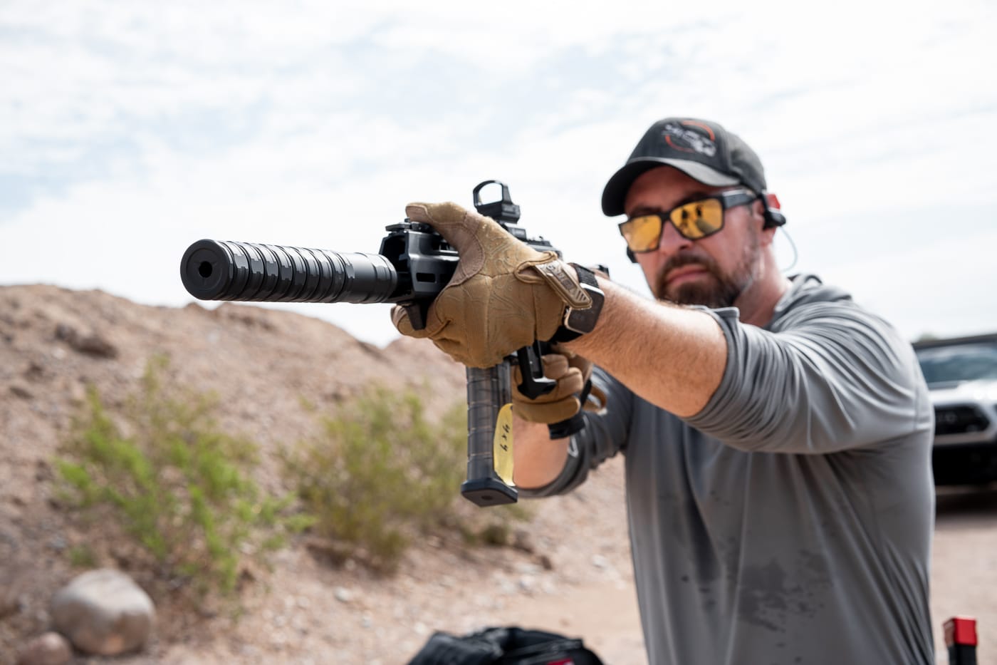 An action photograph showing the reviewer firing the suppressed Springfield Armory Kuna with the JK Armament RPX 9mm attached during hands-on range evaluation. The JK Armament 155 RPX 9mm suppressor review prioritized practical testing. Live fire demonstrates suppressor sound reduction effectively. The Kuna provides a stable shooting platform. Suppressed firearms enhance situational awareness downrange. Shooters experience less auditory fatigue with silencers. The modular suppressor performed reliably throughout testing. Reduced report improves range communication significantly. Real-world evaluation matters more than specifications alone.