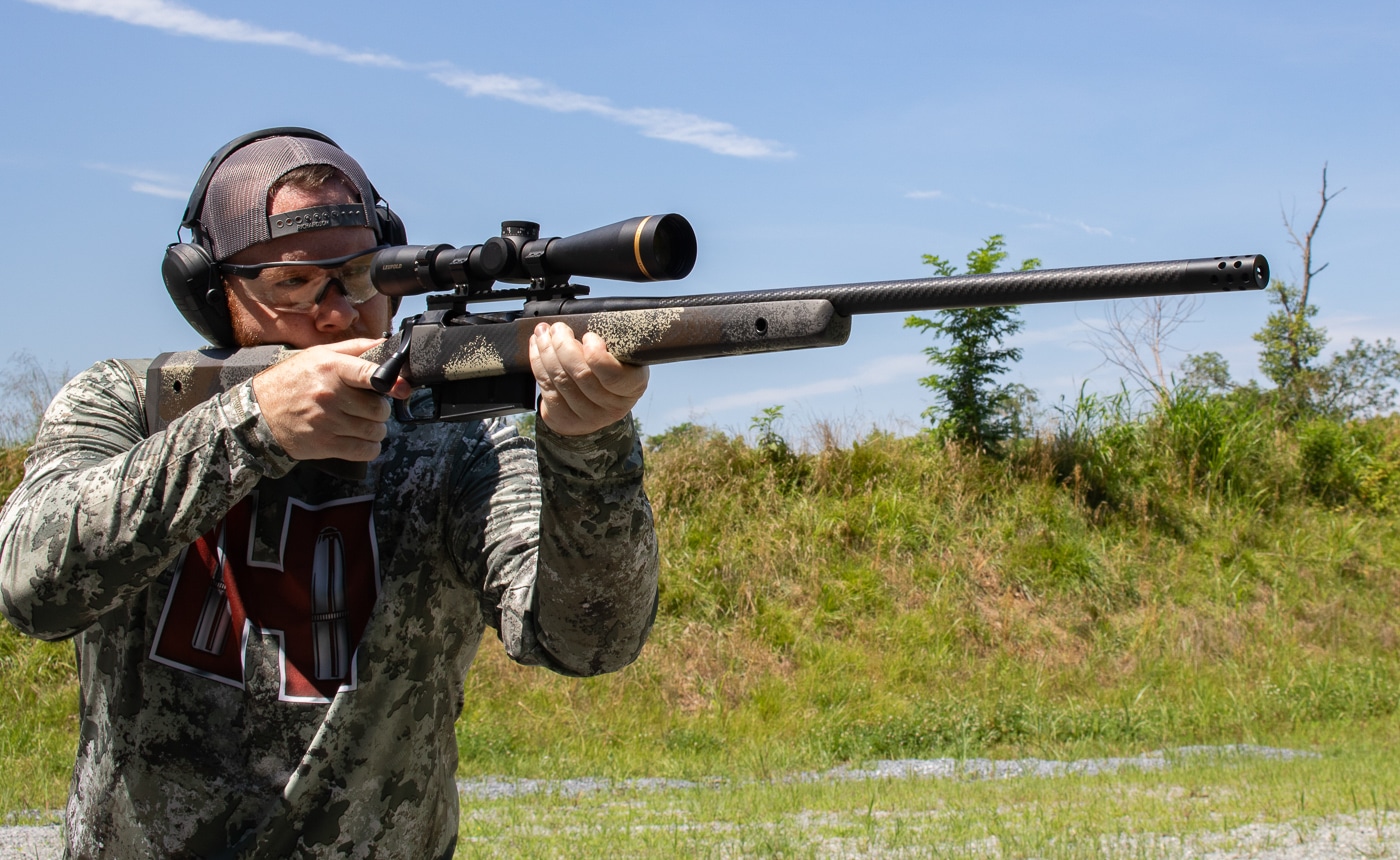 A shooter positioned behind the Springfield Model 2020 Waypoint rifle at the range demonstrating proper shooting form with the modernized stock ergonomics. The Model 2020 Waypoint features enhanced ergonomic design elements. AG Composites stocks provide raised combs for optic alignment. The 7mm PRC generates manageable recoil for extended shooting sessions. Springfield's Waypoint platform encourages proper shooting technique naturally. Vertical pistol grips improve trigger control and stability. The author tested the rifle extensively before field deployment. The 7mm PRC Model 2020 Waypoint suits shooters of varying experience levels. Practice with hunting rifles builds proficiency for ethical shots.