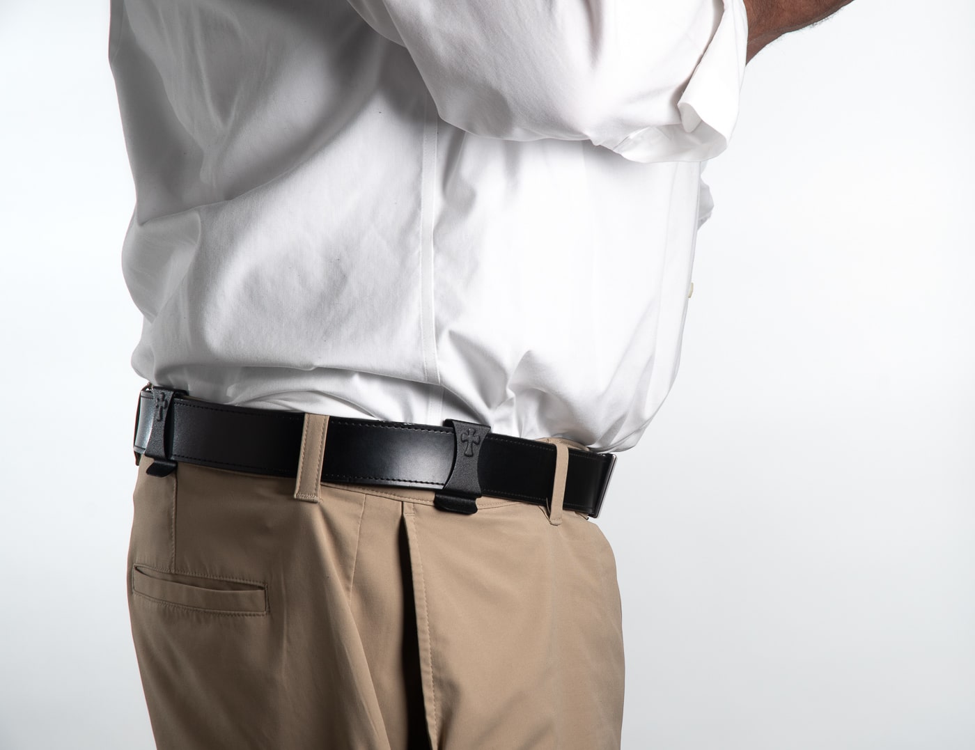 A close-up photograph shows exposed holster clips protruding above a waistband with a tucked dress shirt, revealing the telltale signs of concealed carry. Concealed carry at work requires complete discretion. Workplace CCW demands hidden retention systems. Office carry suffers from visible clips. CCW at the office needs better concealment methods. Professional environments expose tuckable holster limitations. Business attire reveals traditional holster clips. Concealed carry at work means avoiding detection. Office defense includes truly hidden systems.