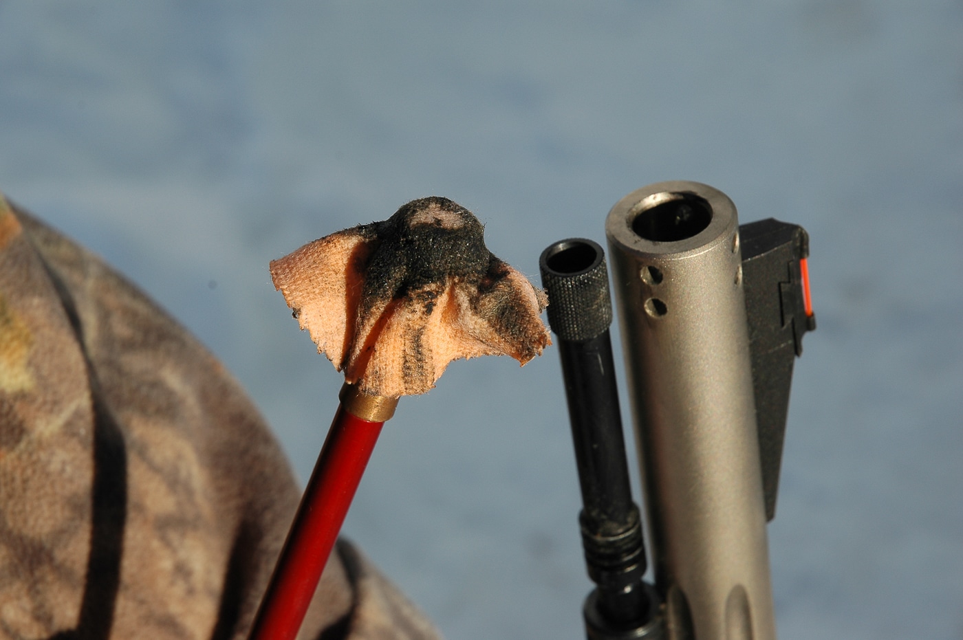 A close-up photograph shows thick black residue and crusty deposits coating metal surfaces after black powder combustion, with heavy carbon buildup and corrosive salts visible as dark, flaky material. Black powder combustion produces substantial fouling. Gunpowder history includes residue management challenges. Saltpeter leaves corrosive deposits after burning. Charcoal creates carbon buildup rapidly. Origins of gunpowder involved accepting dirty combustion. Sulfur compounds corrode metal surfaces. Shooters cleaned firearms between shots frequently. Ancient propellants required constant maintenance procedures.
