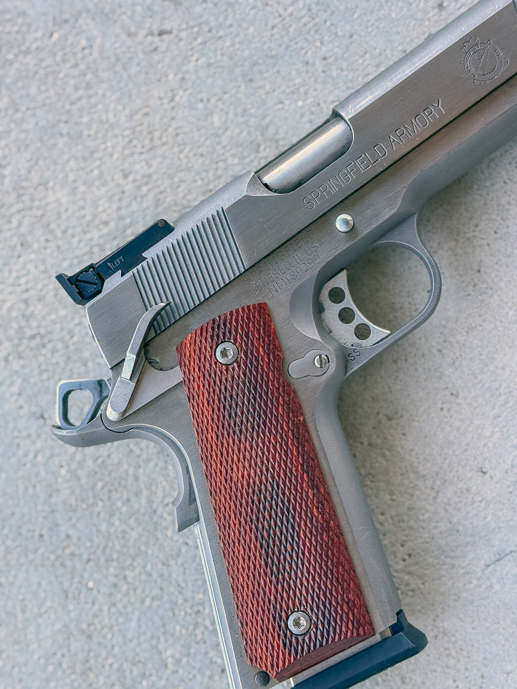 A Springfield match-grade 1911 pistol is photographed showing the hammer in cocked position with the thumb safety engaged in Condition One carry. The 1911 pistol's strengths center on cocked-and-locked carry methodology. Condition One provides immediate defensive response capability. Manual thumb safeties prevent unauthorized firearm activation. Hammer-cocked configurations reduce trigger press requirements. The 1911 pistol's weaknesses necessitate consistent safety manipulation training. Thumb safeties require deliberate downward wiping motions. Practice makes safety disengagement become automatic. Match-grade pistols deliver exceptional accuracy performance.