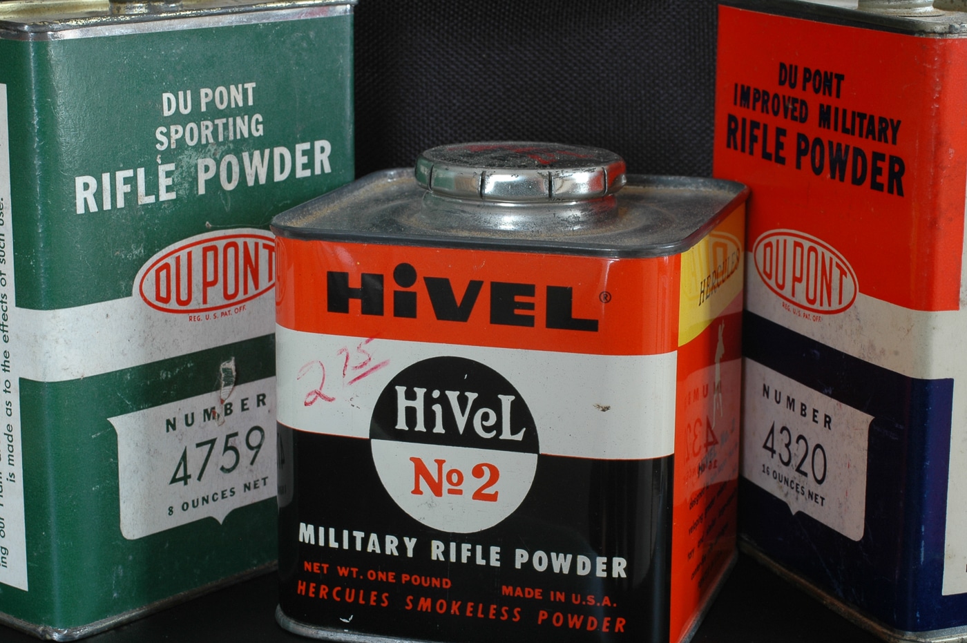 A collection of vintage metal powder canisters displays various brands and types of early smokeless gunpowder, with labels showing manufacturer names and powder designations from the early-to-mid 20th century. Gunpowder history shifted dramatically during the 1890s. Nitrocellulose-based propellants replaced black powder formulations. Smokeless powder origins trace to European chemists. Single-base propellants contained no nitroglycerin additives. Origins of gunpowder evolved through chemical innovations. Double-base formulas incorporated multiple compounds. DuPont and Hercules dominated American markets. Ancient black powder became obsolete technology.