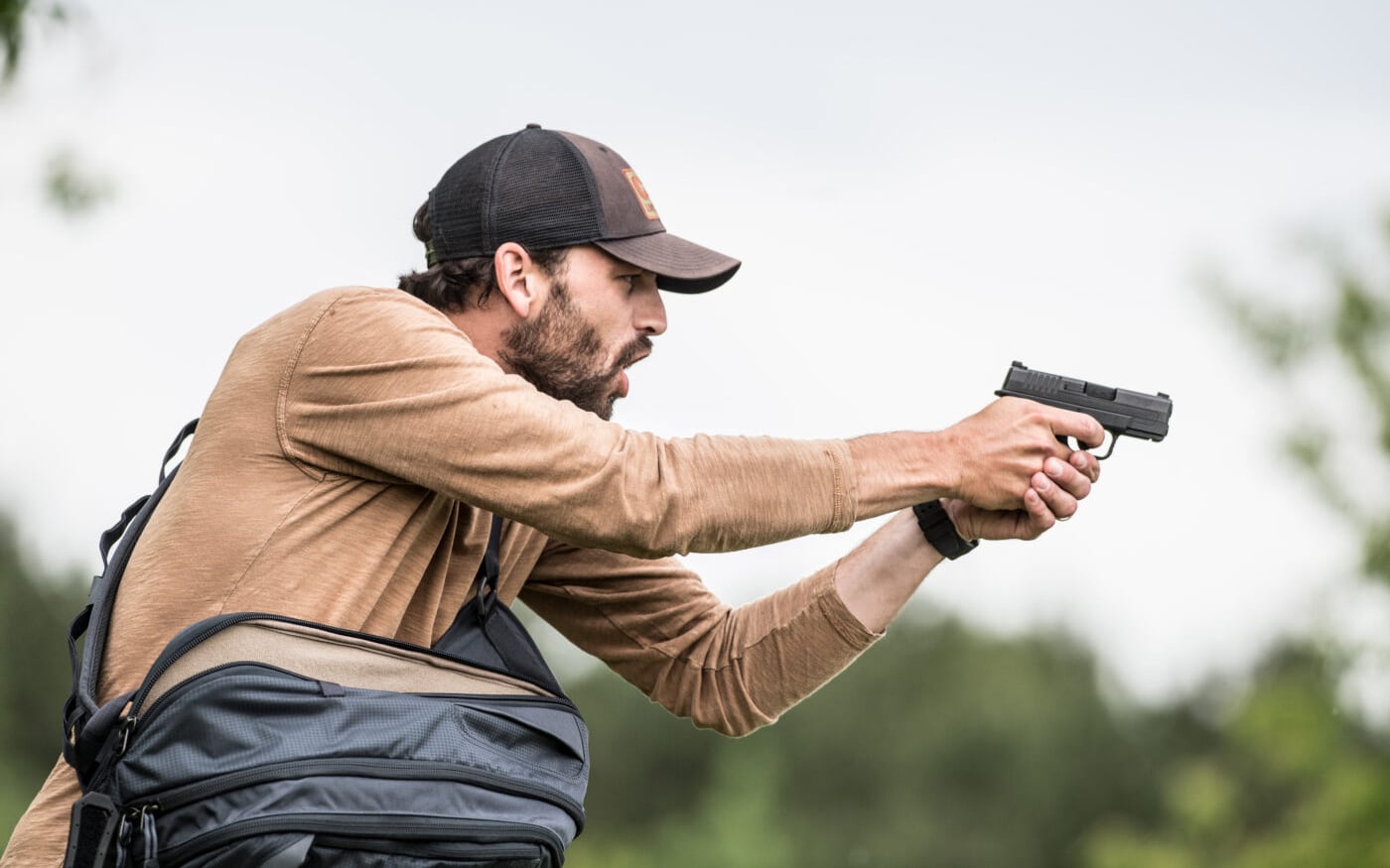 Man shooting pistol in self-defense while carrying a backpack