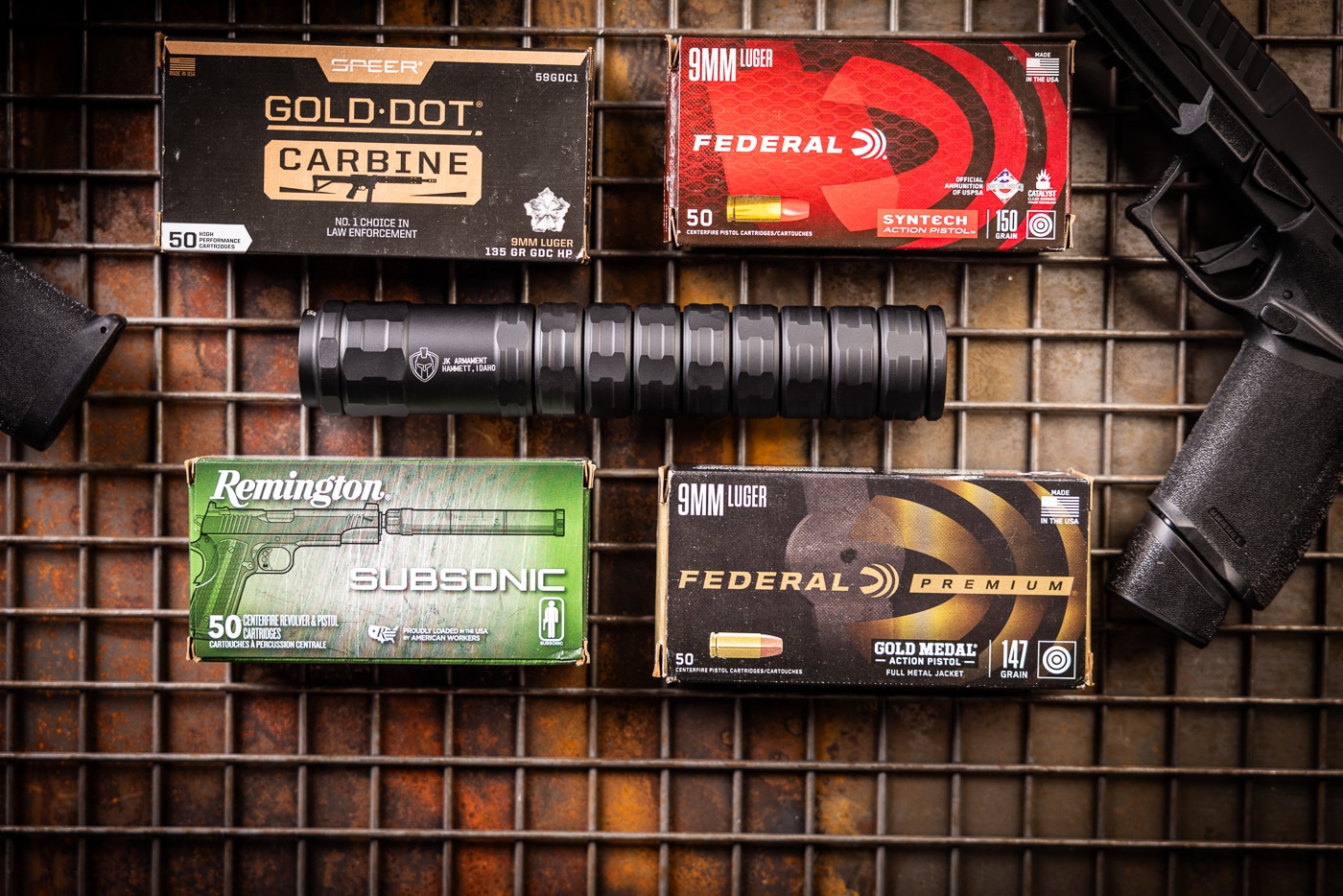 An authentic product photograph showing the JK Armament 155 RPX suppressor reviewed by the author positioned with the Federal, Remington, and Speer ammunition used during range testing. The JK Armament 155 RPX 9mm suppressor review prioritized genuine evaluation. This silencer fired hundreds of rounds during testing. Ammunition selection impacts suppressor performance significantly. The RPX features Cerakote and hard-anodized finish protection. Heavier bullets optimize sound reduction when suppressed. Real gear reviews provide trustworthy buyer information. The modular design allows length and weight customization. Shooters benefit from honest hands-on suppressor evaluations.