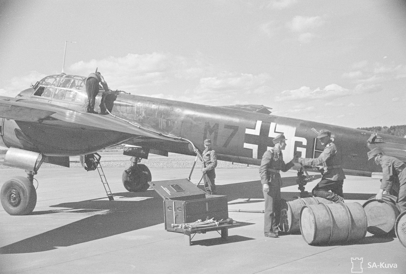 Ground crew members refueling a Junkers Ju 88 bomber at a Finnish airbase in preparation for an upcoming combat mission. The Ju 88 bomber served with allied air forces. Finnish aviation operated German-supplied aircraft. Arctic theater operations required cold-weather preparation. Fuel servicing preceded every combat sortie. Allied nation air forces utilized Ju 88 variants. Northern airfields supported anti-Soviet missions. Ground crews maintained aircraft under harsh conditions. Historical images document international Ju 88 operations.