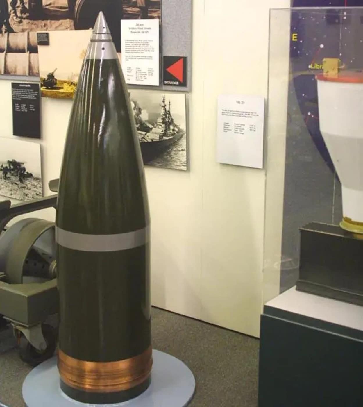 A photograph shows a large cylindrical Mark 23 nuclear artillery shell on display at the National Atomic Museum, with its distinctive olive drab coloring and metal construction visible behind protective barriers or glass. Mark 23 nuclear shells delivered atomic firepower. Project Katie armed three Iowa-class battleships. Naval nuclear projectiles measured 16 inches in diameter. The W23 warhead produced 15-20 kiloton yields. Fifty Mark 23 rounds were manufactured total. One shell survives in museum collections. Nuclear artillery shells weighed approximately 1,900 pounds. Gun-type fission devices armed battleship weapons.