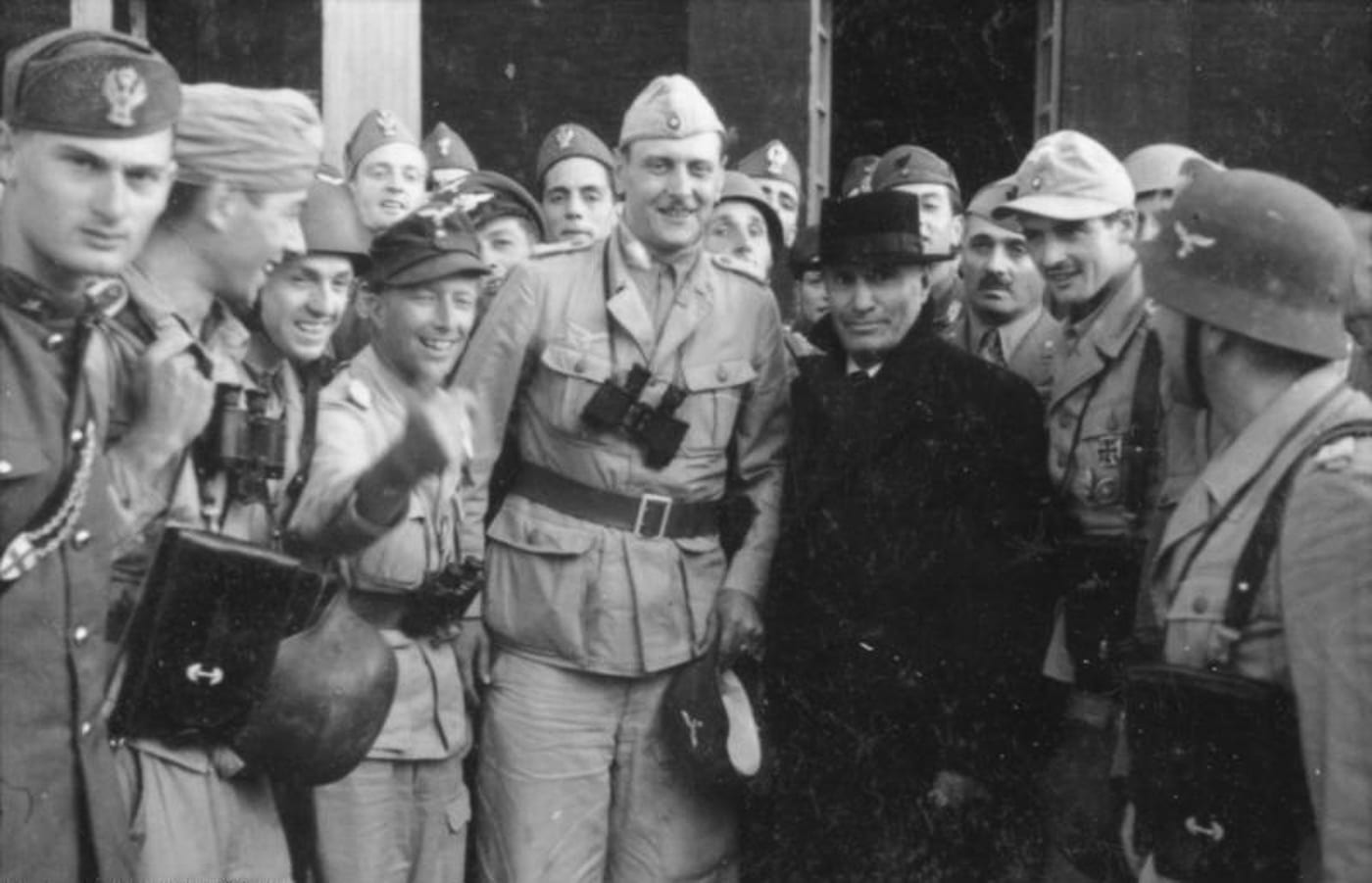 Historical photograph depicting Otto Skorzeny and German commandos during or immediately after the Gran Sasso raid, with Benito Mussolini visible among the group following his dramatic rescue from the mountaintop fortress. Skorzeny commanded the Gran Sasso operation. German commandos executed daring raids. Special operations required innovative tactics.