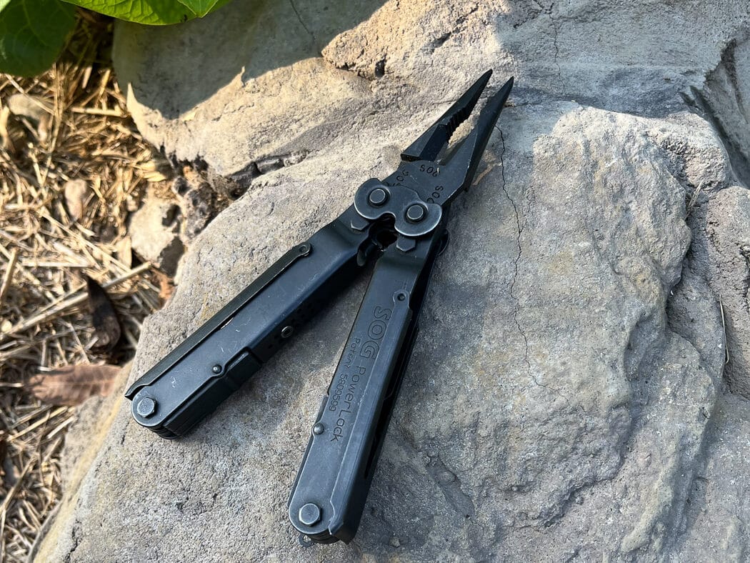 A SOG Power Lock multi-tool shown in its open position, displaying pliers, knife blade, and various integrated tools within hinged handle covers. Fieldcraft knives require supplemental tools for detailed work. Multi-tools provide compact versatility. Dale Dye field craft knife opinions accept practical tool consolidation.
