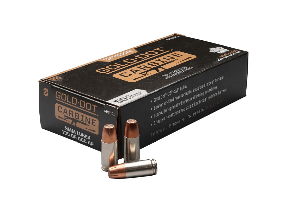 A box of Speer Gold Dot Carbine ammunition sits open displaying the nickel-plated cartridges with visible hollow-point bullets inside. Speer Gold Dot Carbine ammunition comes in distinctive packaging. PCC ammo uses 135-grain G2 projectiles. The cartridges feature nickel-plated brass construction. Gold Dot loads target pistol caliber carbine platforms. Pistol caliber carbines require optimized ammunition loads. The Speer Gold Dot Carbine review evaluated production ammunition. Carbine-specific loads differ from standard pistol ammunition. Springfield Armory SAINT Victor benefits from tailored loads.