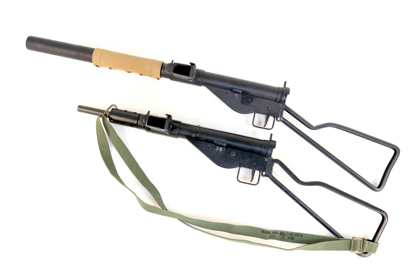 Comparative display of a regular Sten submachine gun alongside its silenced Mk IIS counterpart, clearly showing the suppressor's additional length and the canvas heat shield protecting operators' hands. Silenced Sten Mk IIS expanded operational capabilities. Standard Stens generated significant muzzle blast. The suppressed variant featured ported barrels. Wire-mesh baffles contained propellant gases effectively. Commando units preferred sound-reduced weapons. British engineers modified existing SMG designs. Subsonic rounds prevented supersonic cracks. Special forces utilized suppressed 9mm platforms.