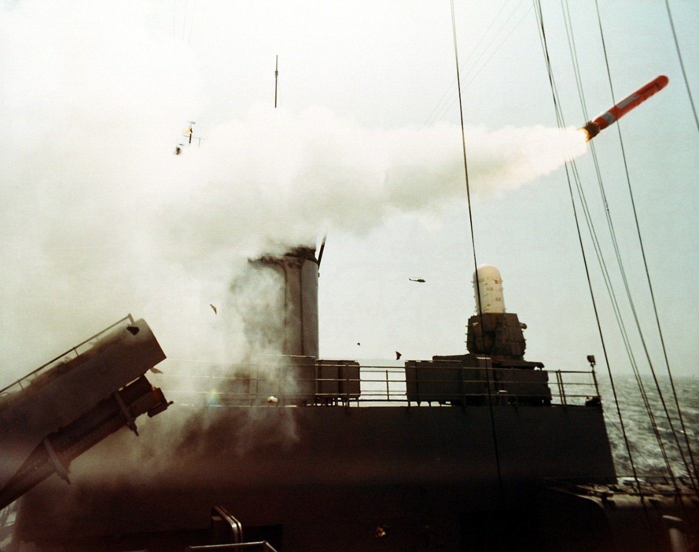 A photograph captures a Tomahawk cruise missile launching from a naval vessel in 1983, with bright rocket exhaust and smoke trailing as the missile begins its flight, demonstrating the operational capabilities of the TLAM-N nuclear weapons system. Tomahawk missiles replaced Mark 23 nuclear shells. Project Katie ended before cruise missile development. TLAM-N testing occurred throughout the 1980s. BGM-109A variants carried W80 nuclear warheads. Cruise missiles achieved 2,500-kilometer operational ranges. Solid propellant boosters initiated missile launches. Turbofan engines propelled Tomahawks to targets. Nuclear deterrence continued through missile systems.