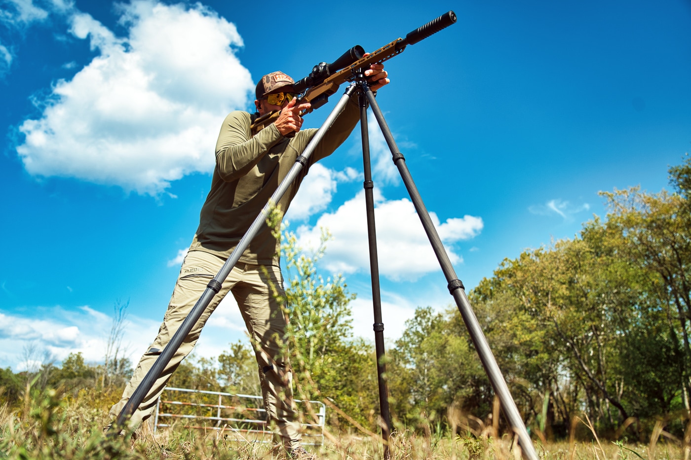 A carbon fiber Tricer-HK tripod with inverted legs is set up on a shooting range with a rifle mounted on top. The Tricer-HK tripod review demonstrates exceptional stability. Ultra light Tricer-HK tripod evaluation confirms minimal flex. Inverted leg design reduces leverage effectively.