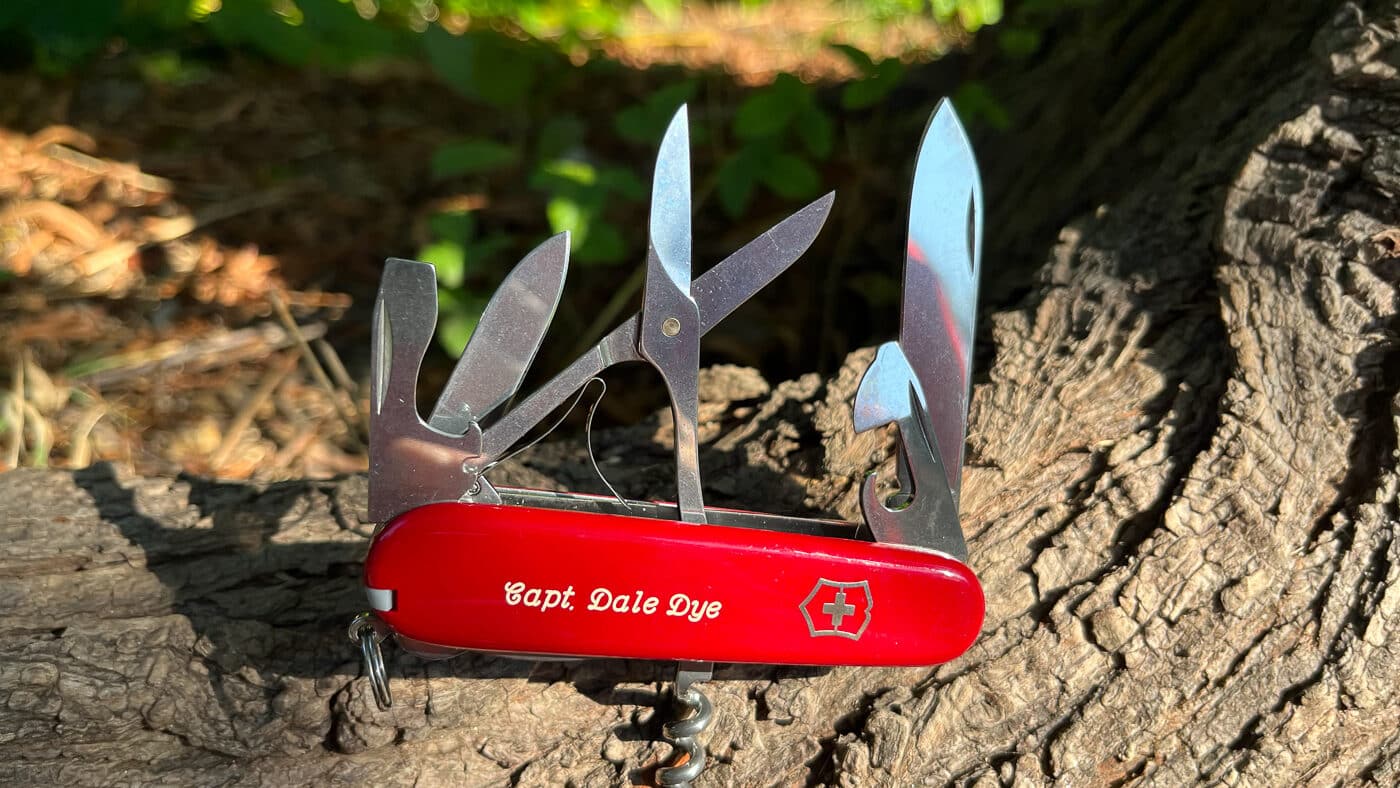 A red-handled Victorinox Swiss Army Knife with multiple folding tools visible, including scissors, blades, and a corkscrew in the classic multi-tool configuration. Fieldcraft knives require more robust construction. Gentleman's pocketknives serve different purposes. Dale Dye field craft knife opinions distinguish appropriate tool applications.