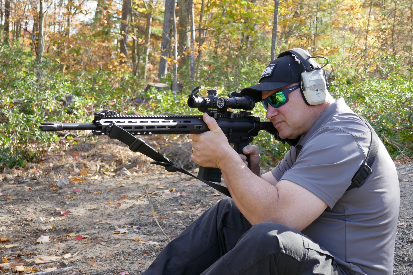 A shooter in seated position on the ground engaging targets with the Springfield Armory SAINT Victor 7.62x51mm rifle, demonstrating practical field shooting technique and the rifle's adaptability to various shooting positions beyond standard prone or bench setups. The SAINT Victor 7.62 20-inch performs across multiple positions. Springfield rifles maintain accuracy without perfect support. Seated shooting positions provide reasonable stability.