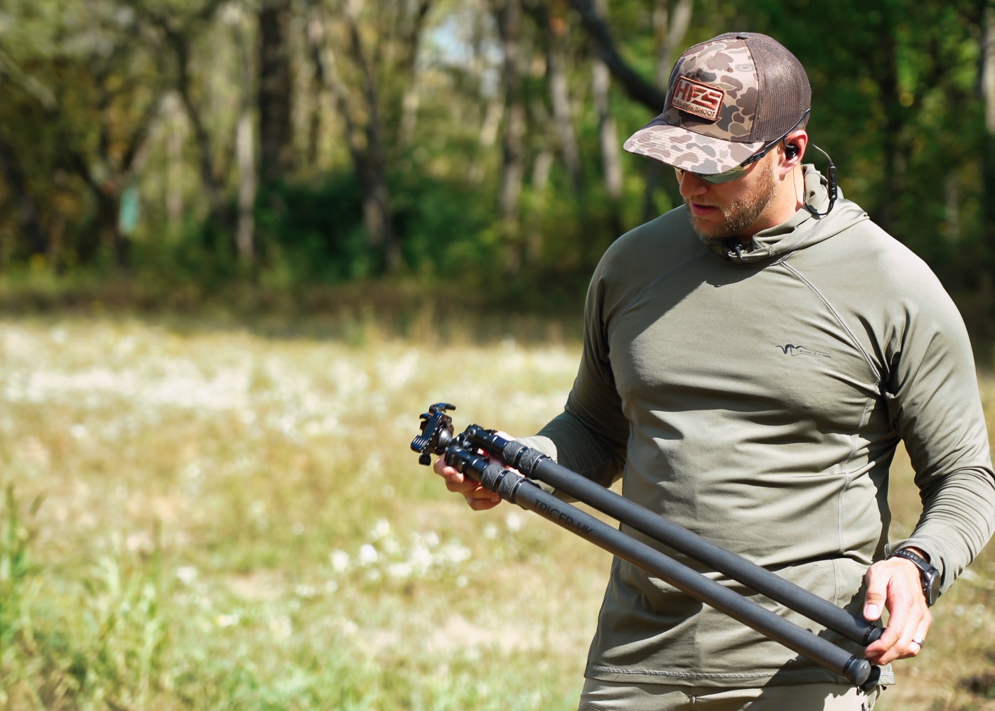 The author adjusts the three-section legs of a Tricer-HK tripod using the twist-lock mechanism while demonstrating its operation. Lightweight shooting tripods require reliable locking systems. The Tricer-HK tripod review emphasizes field usability. Quick-adjust mechanisms benefit precision shooting applications.