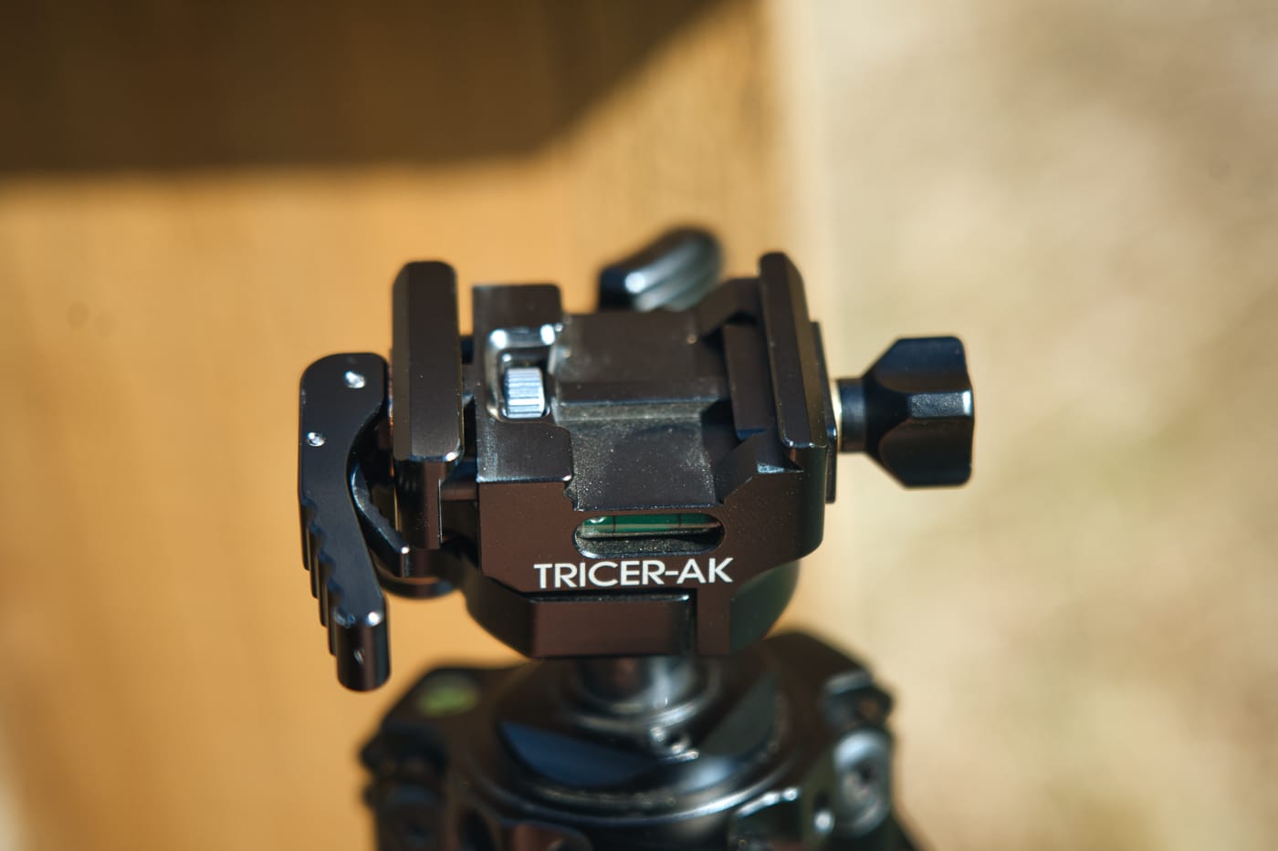 A close-up shows the Tricer-AK Ball Head mounted on top of the Tricer-HK tripod with visible Arca-Swiss and Picatinny rail mounting options. The Tricer-HK tripod review emphasizes mounting versatility. Ultra light Tricer-HK tripod evaluation confirms smooth adjustment capability. Ball head systems enable precise rifle positioning.