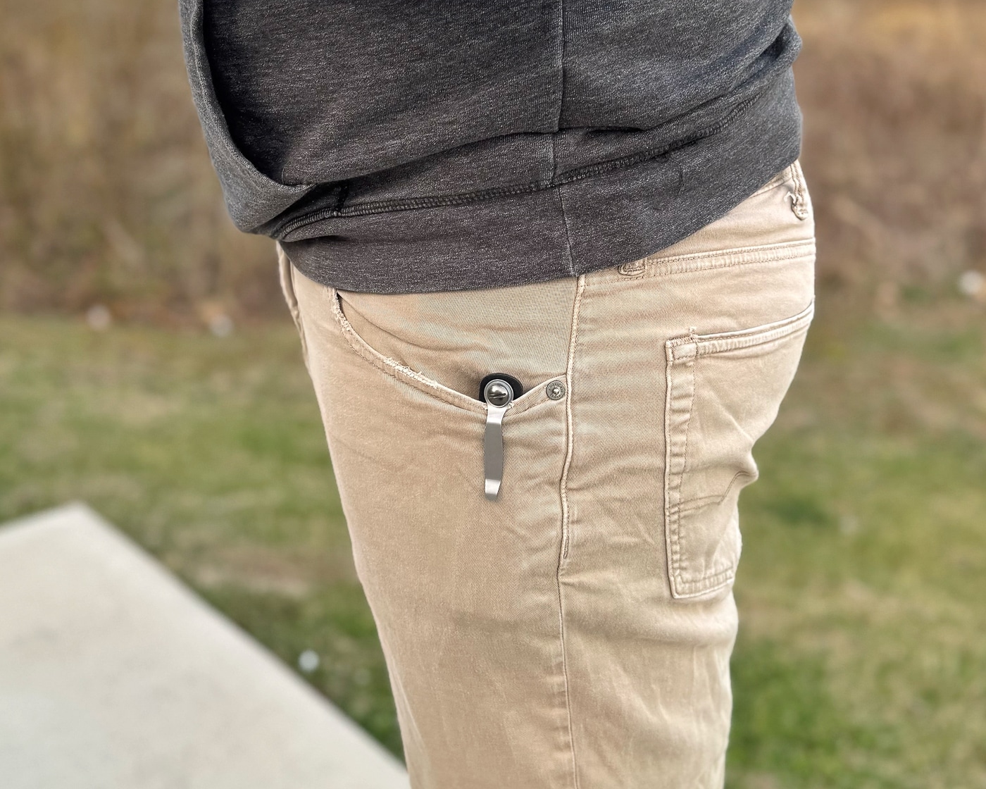 A person carries the ExtraCarry magazine pouch clipped to their pants pocket during field testing, demonstrating how the carrier sits discreetly during actual daily use and movement. ExtraCarry reviews include practical evaluation. Magazine carriers undergo real-world testing. Concealment pouches require comfort verification.