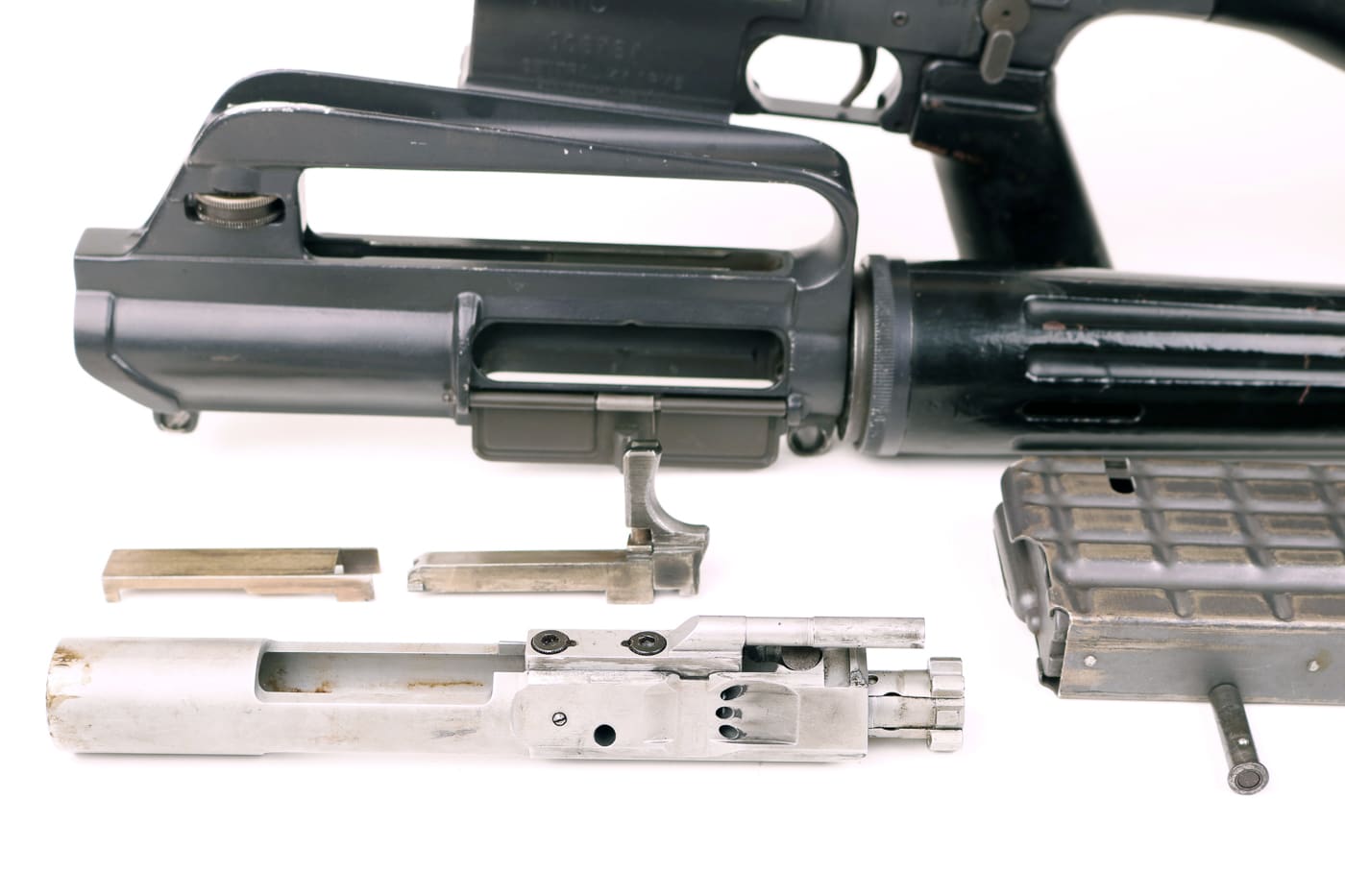 A detailed photograph of the disassembled charging handle assembly from a Dutch AR-10 rifle, revealing the internal components and locking mechanism that engaged the bolt carrier group. The AR-10 employed unique mechanisms. Charging handles featured innovative design. Stoner developed novel solutions. AR10 history includes mechanical experimentation. The assembly locked positively. Dutch components show precision machining. Early systems worked effectively. Forward assist integrated seamlessly.