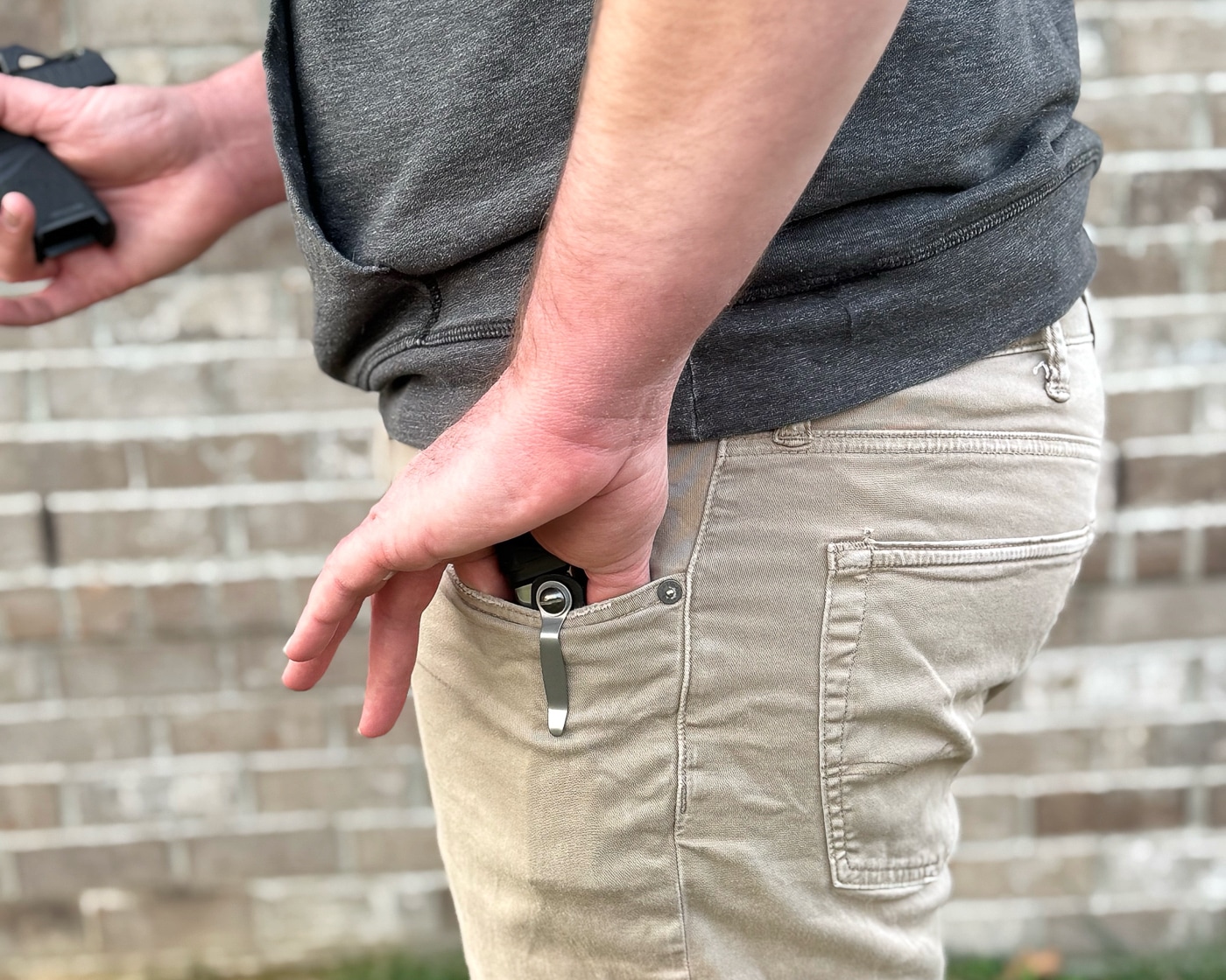 A hand grips and extracts a Hellcat magazine from the ExtraCarry pouch during a draw demonstration, showing the smooth retrieval motion and consistent presentation angle the carrier provides. ExtraCarry reviews assess draw efficiency. Magazine carriers enable rapid access. Reload pouches require predictable presentation.