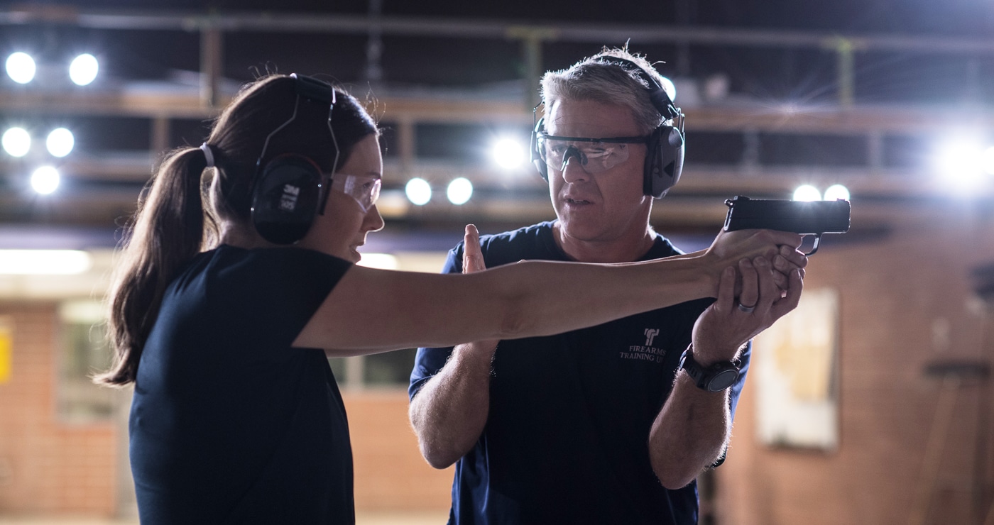 man teaching woman how to shoot a pistol on the shooting range with Steve Tarani techniques